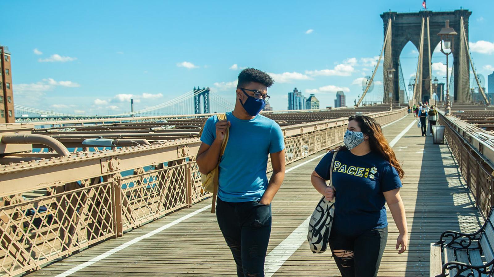 Two Pace University students walking across the Brooklyn Bridge