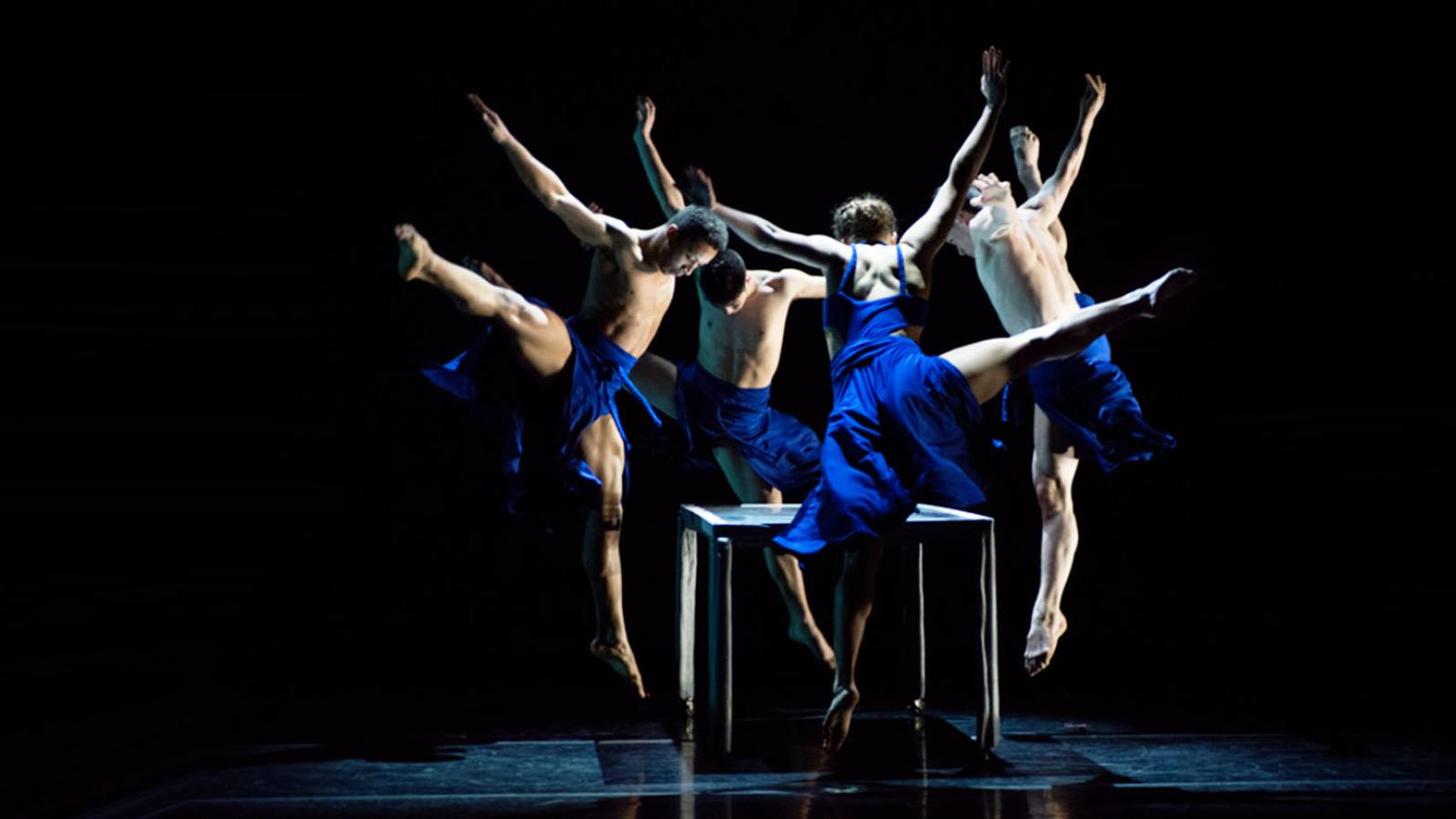 Commercial dance students wearing blue on stage caught in motion
