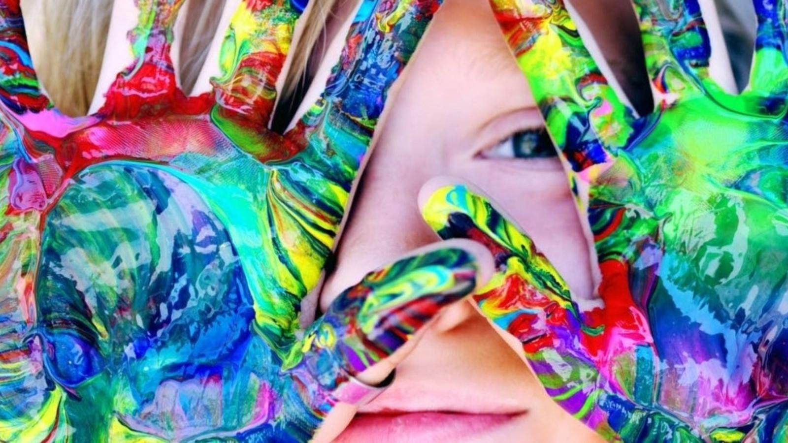 child looking through painted hands