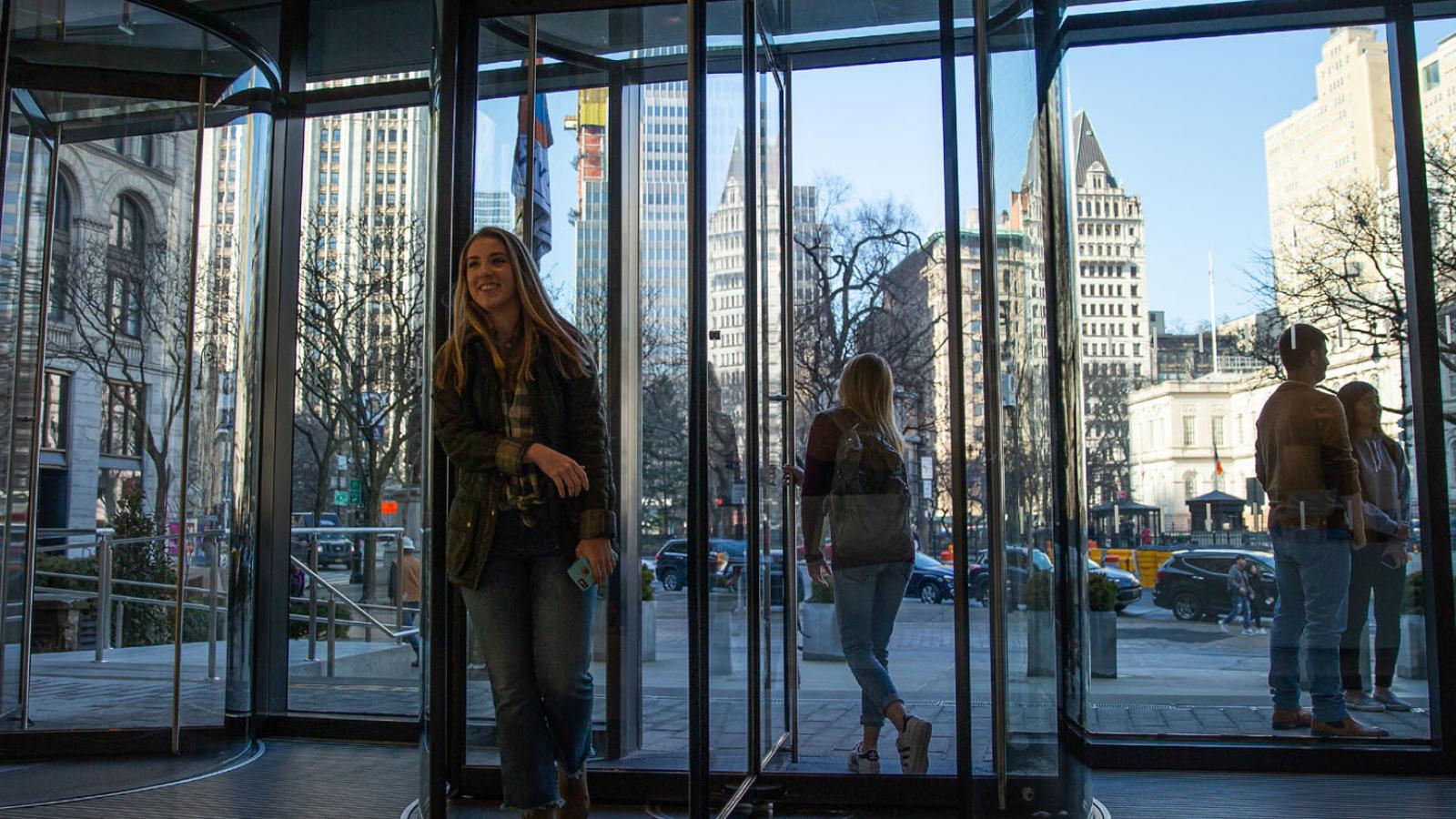 students walking in and out of the front entrance of One Pace Plaza in New York City