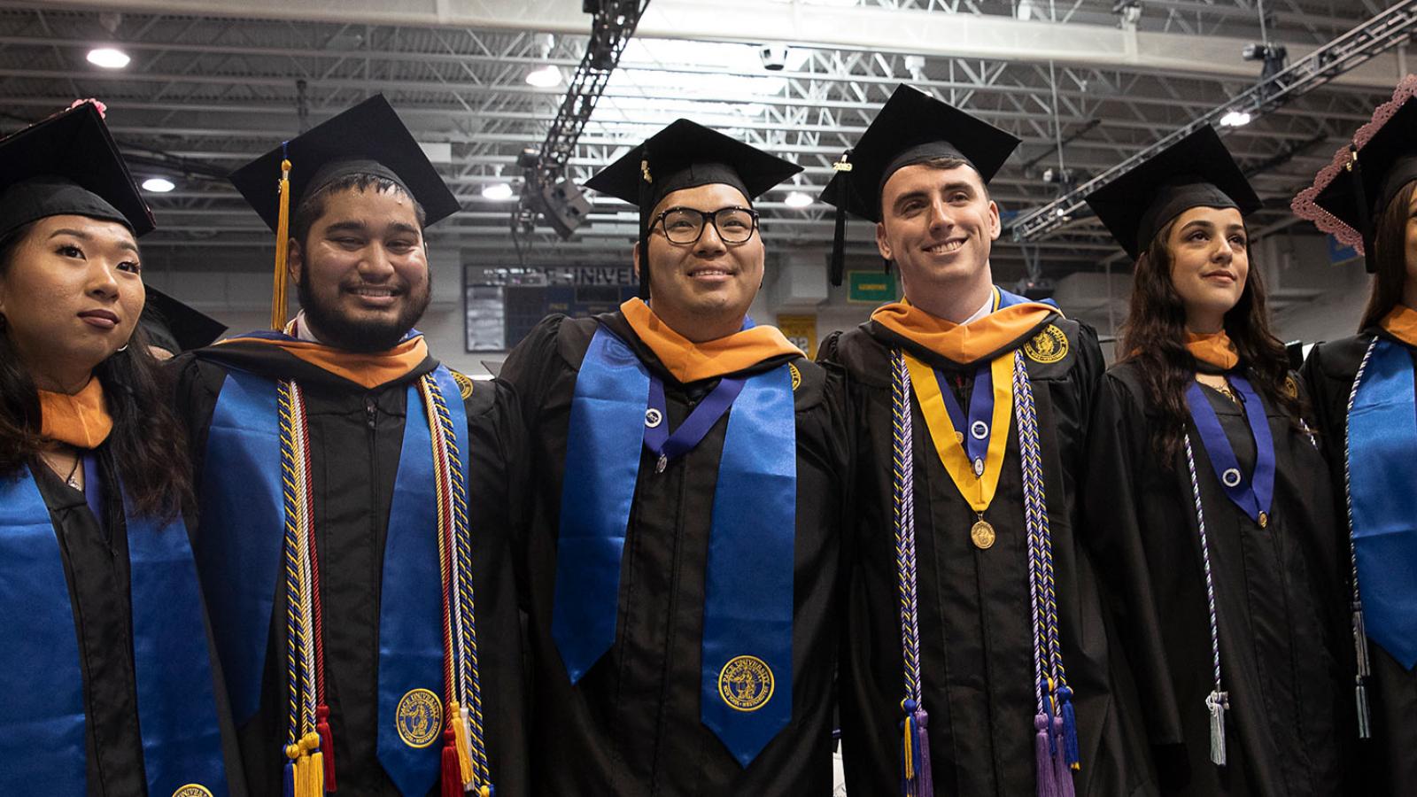 Students in their graduation robes smiling at the camera.