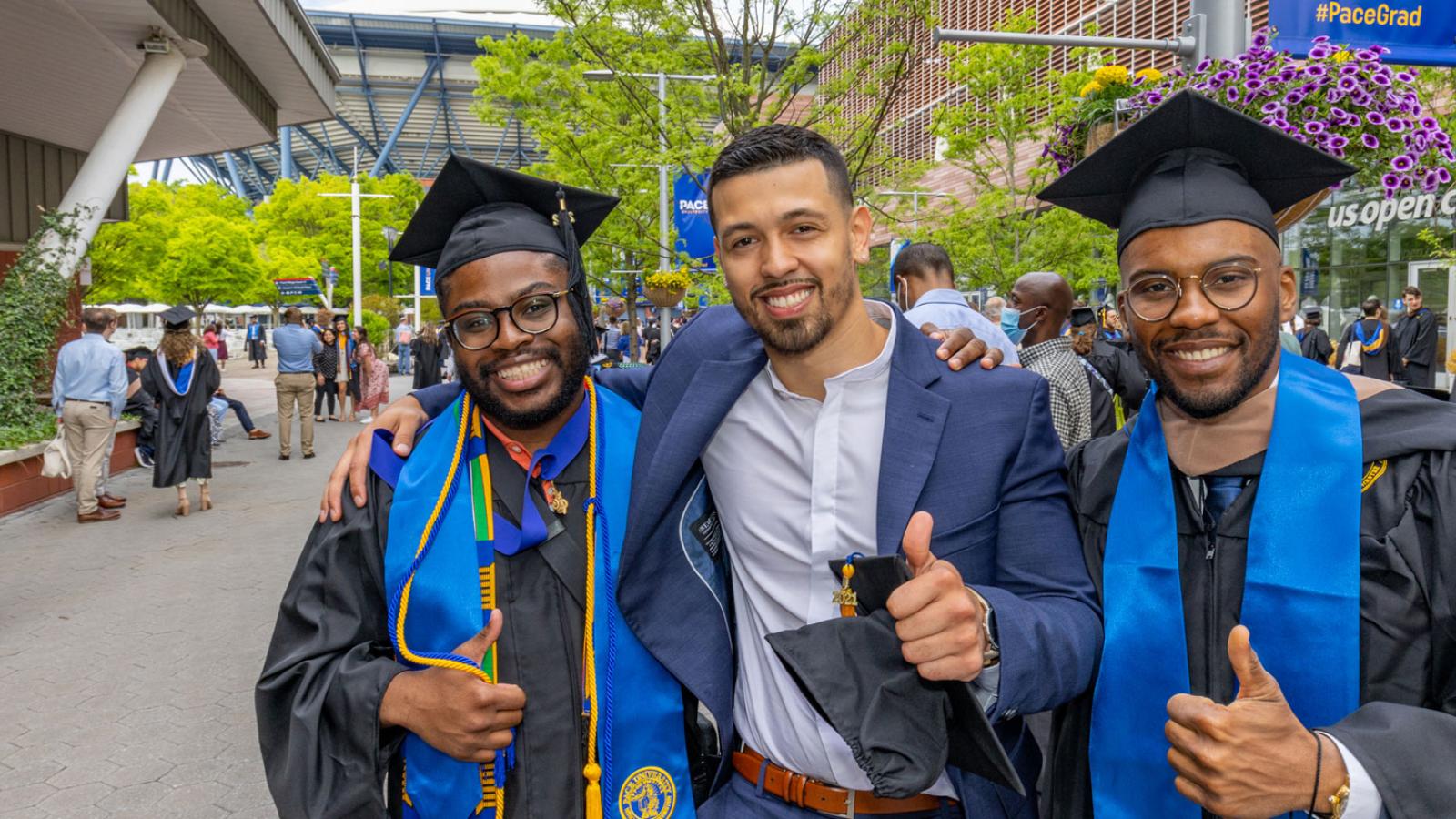 three men in graduation regalia smiling for the camera