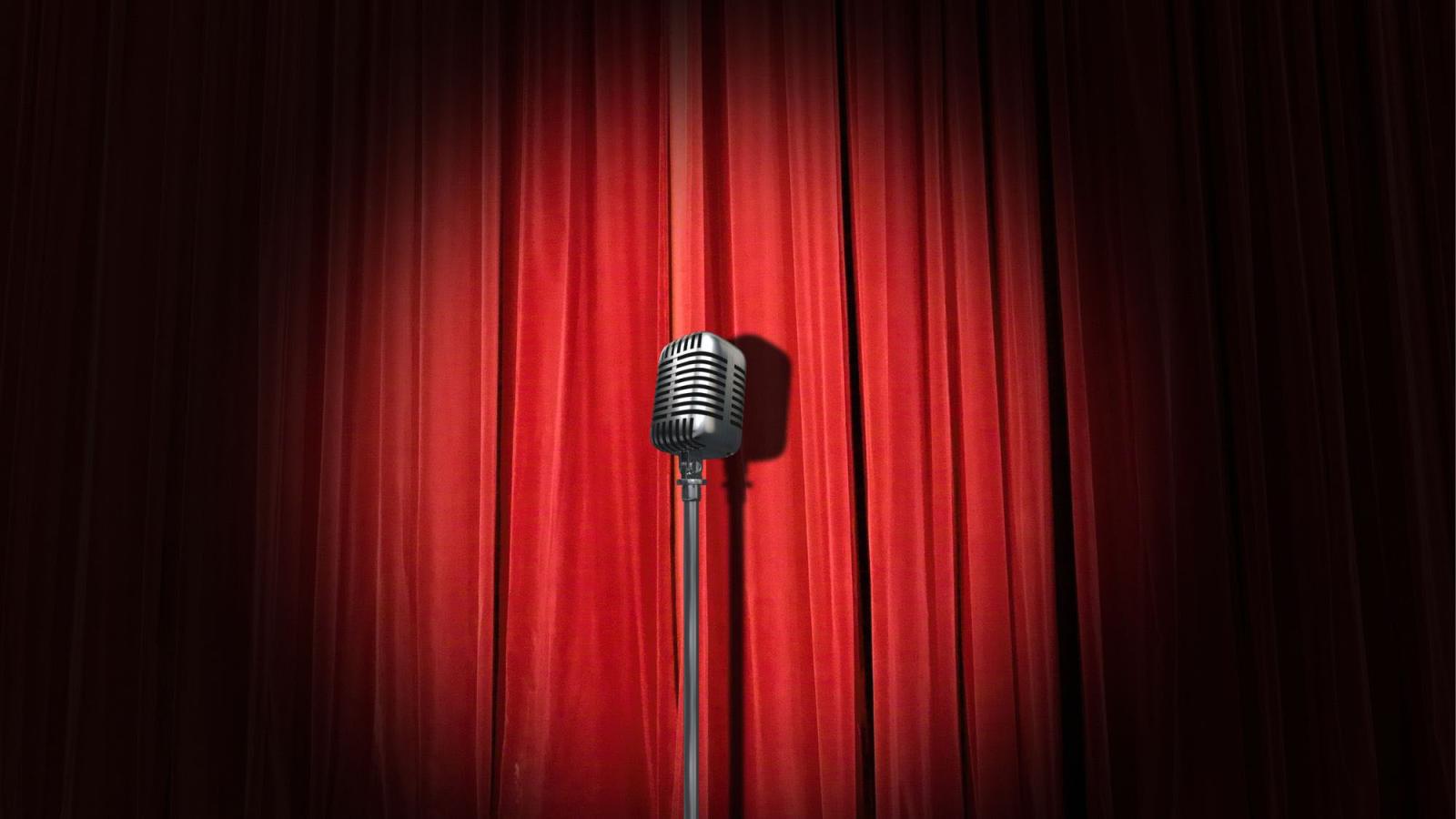 microphone in spotlight against red theater curtains