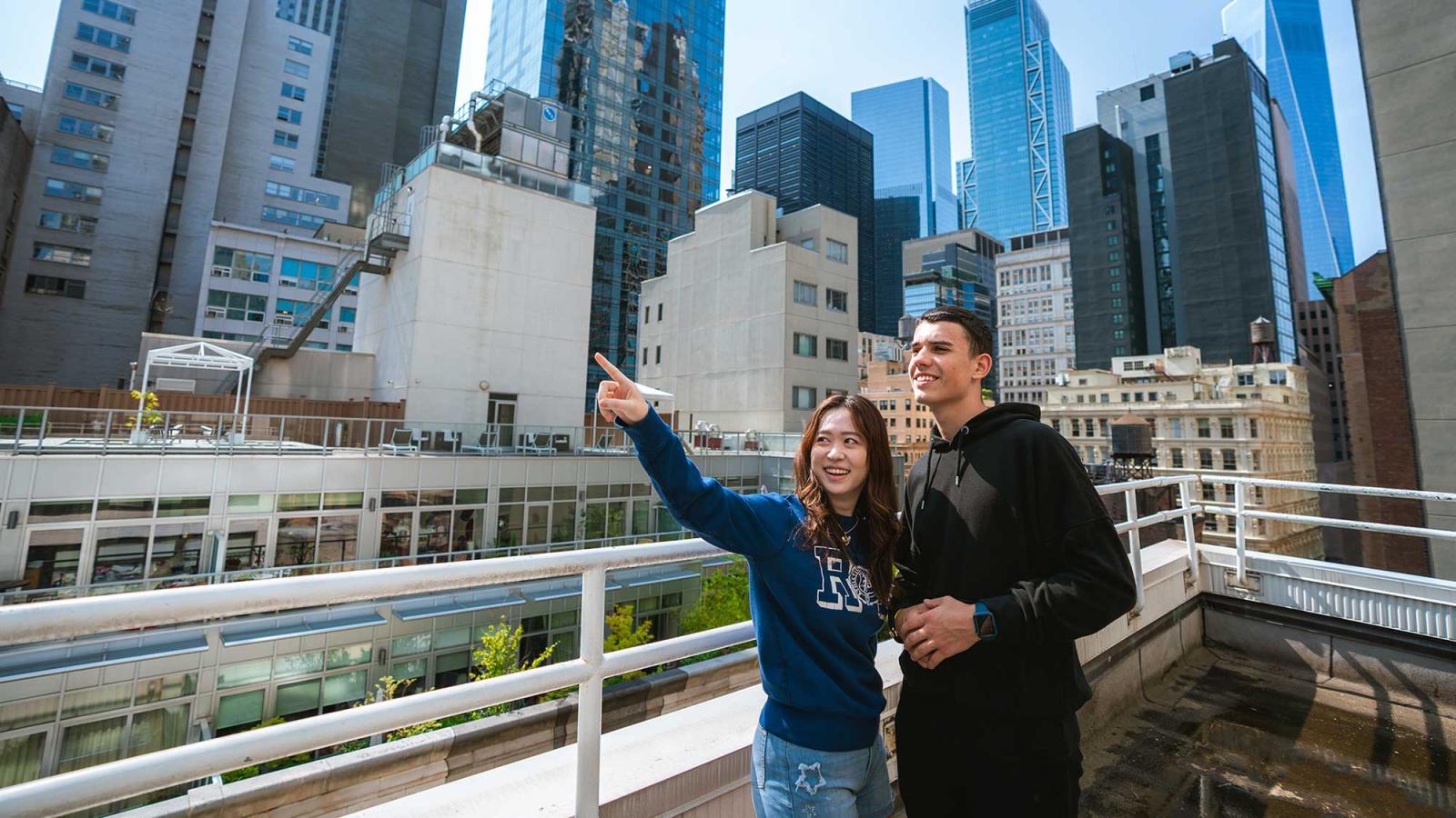 two students on balcony overlooking downtown Manhattan