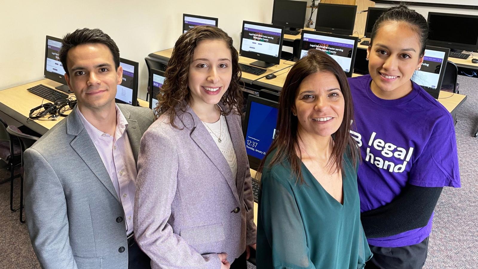 4 students in a computer lab smiling for the camera