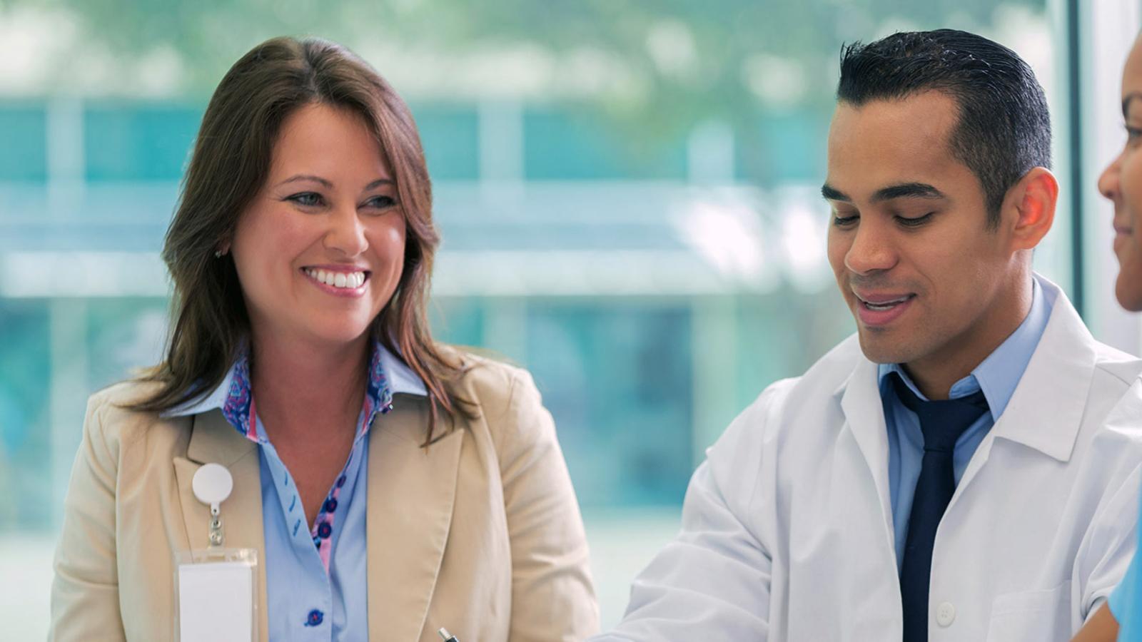 Male doctor speaking with 2 female coworkers