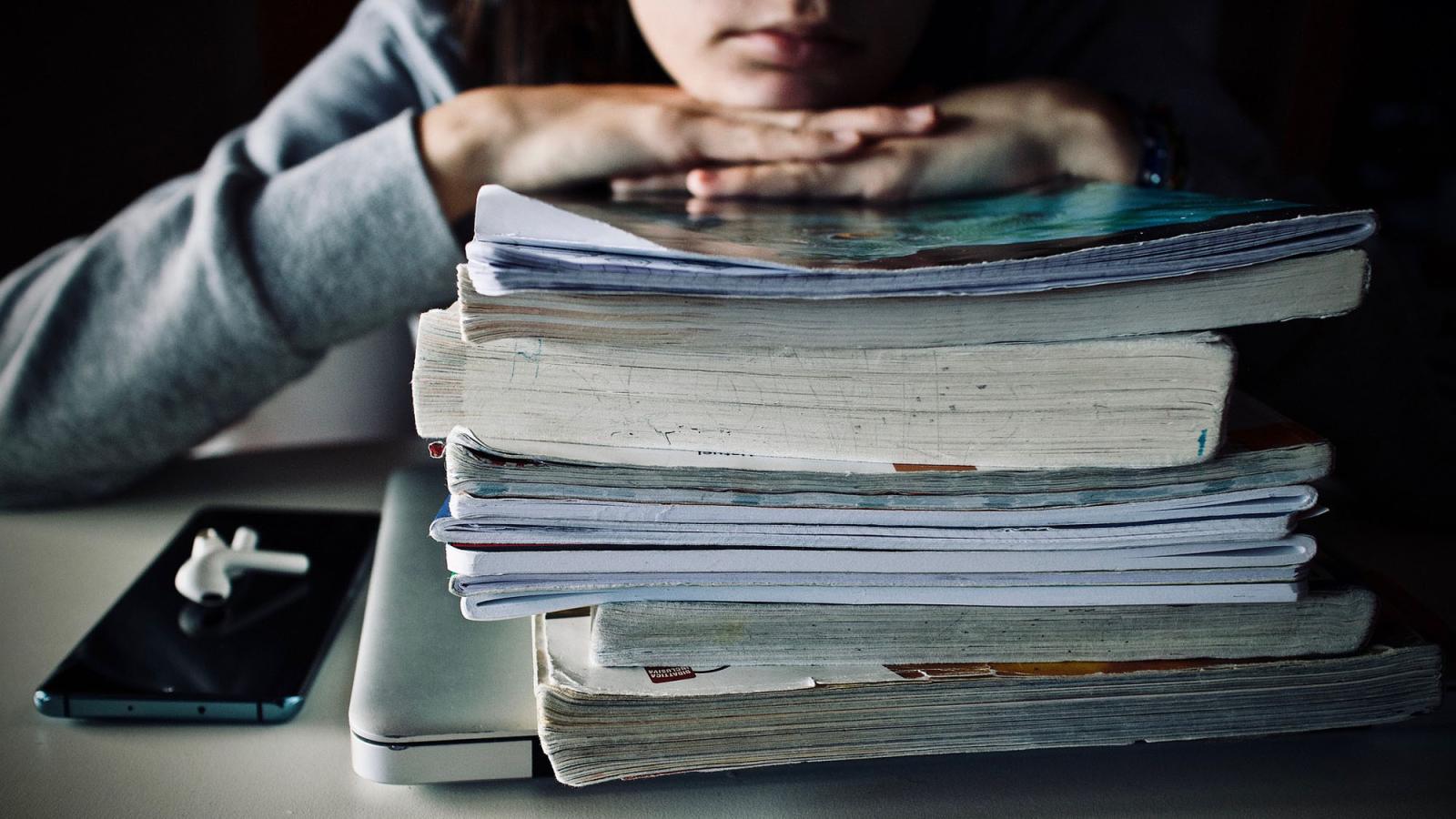 student leaning on a stack of textbooks