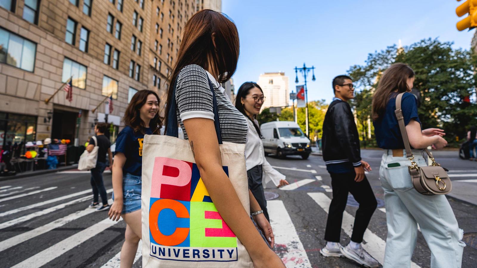 Pace students walking on Lower Manhattan street, with a Pace tote bag the primary focus of the photo