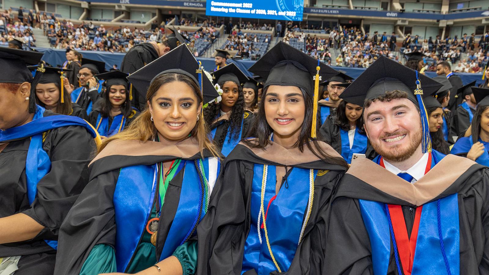 Pace students at their commencement ceremony, smiling at the camera.