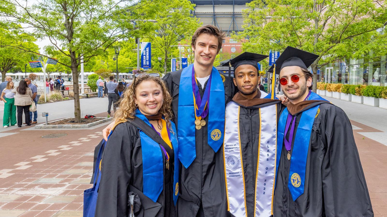 Groups of student at their commencement ceremony, smiling at the camera.