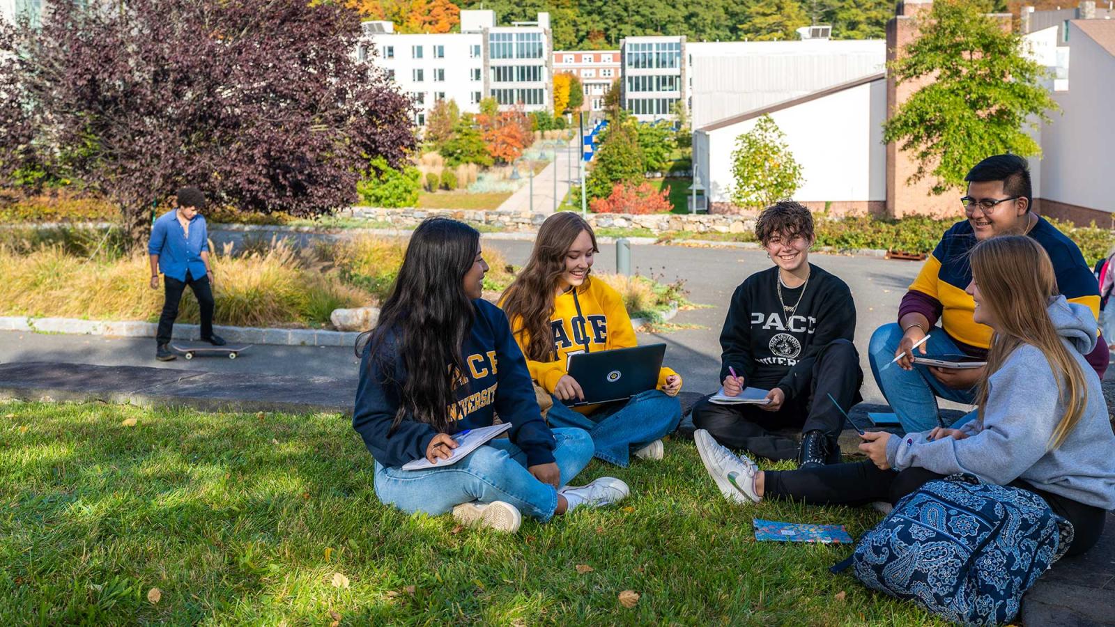 Five students sitting in a circle on lawn in Pleasantville Campus on a sunny day