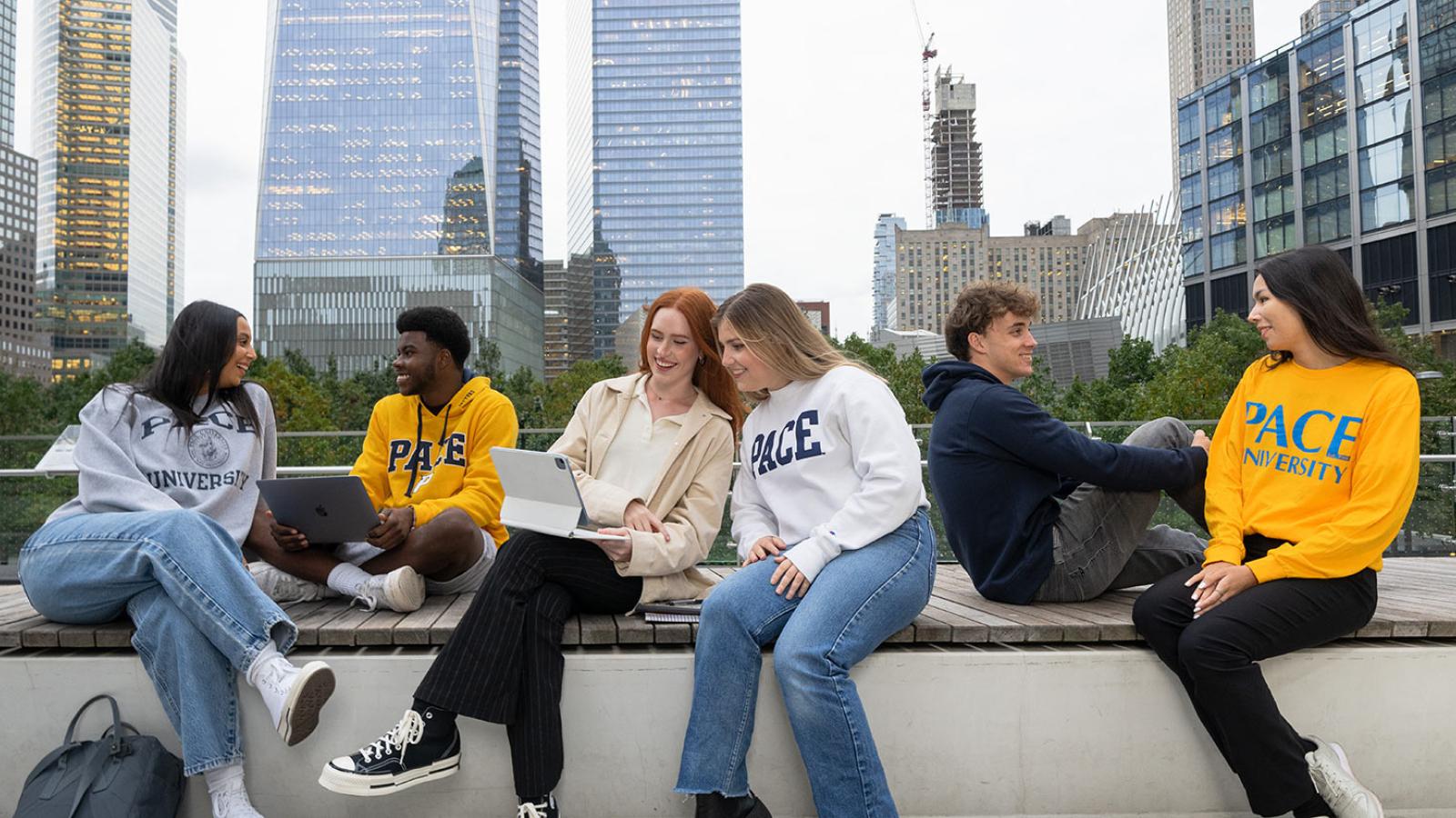 Group of students sitting on a  bench in Manhattan talking and laughing.