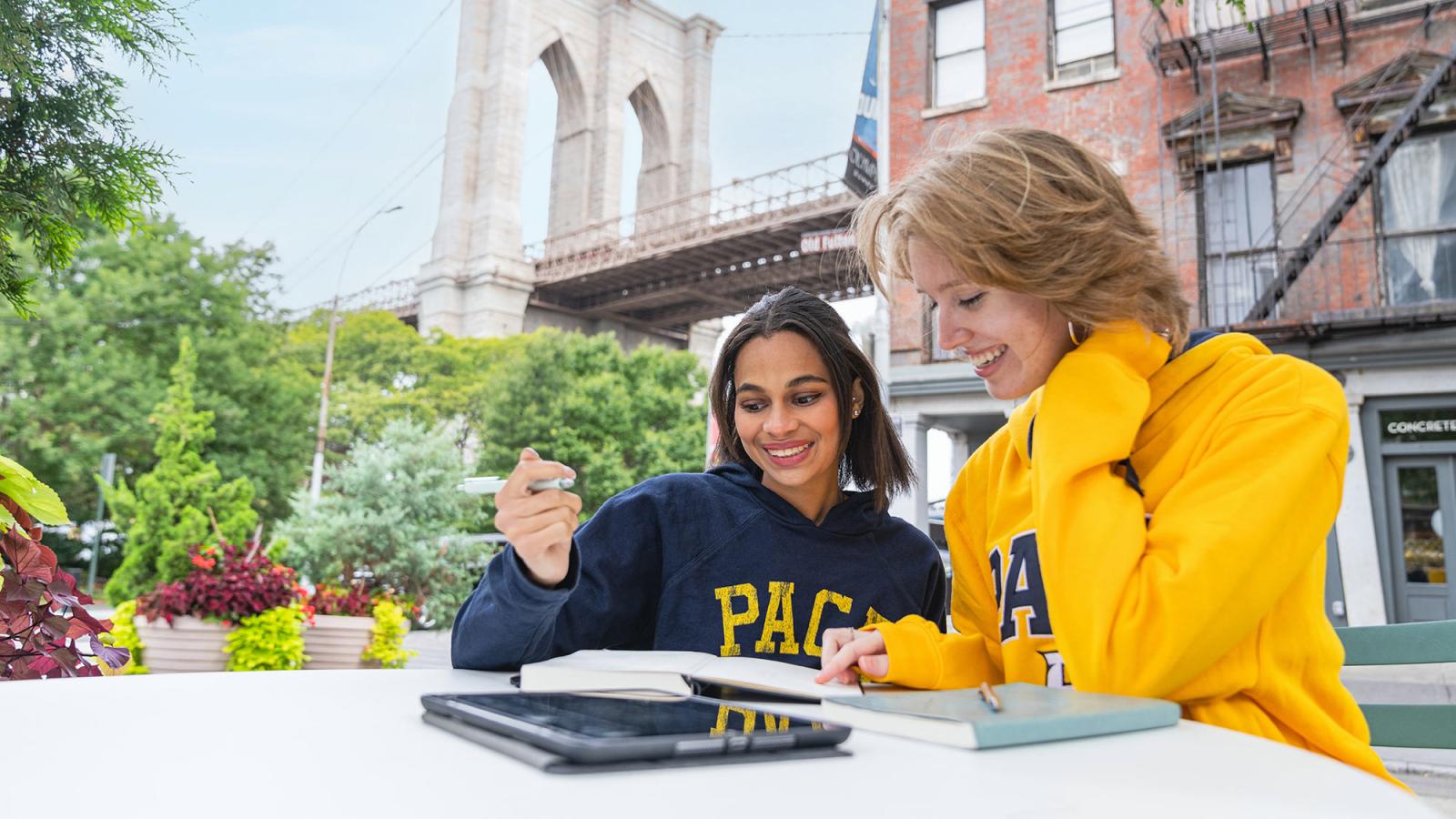 Two students sitting at a table looking at their computers.