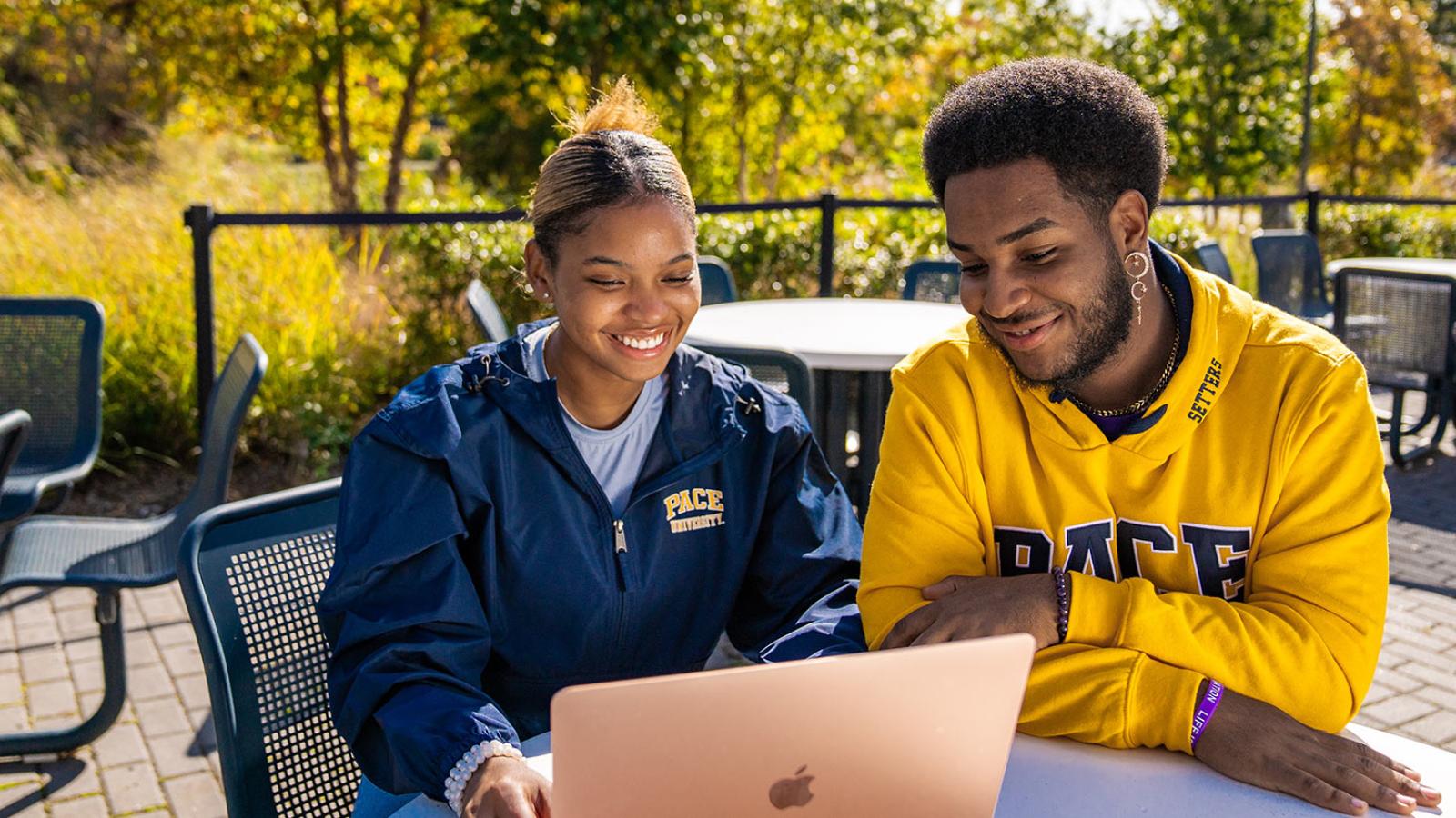 Two students sitting at a table at the Pleasantville campus looking at their laptop.