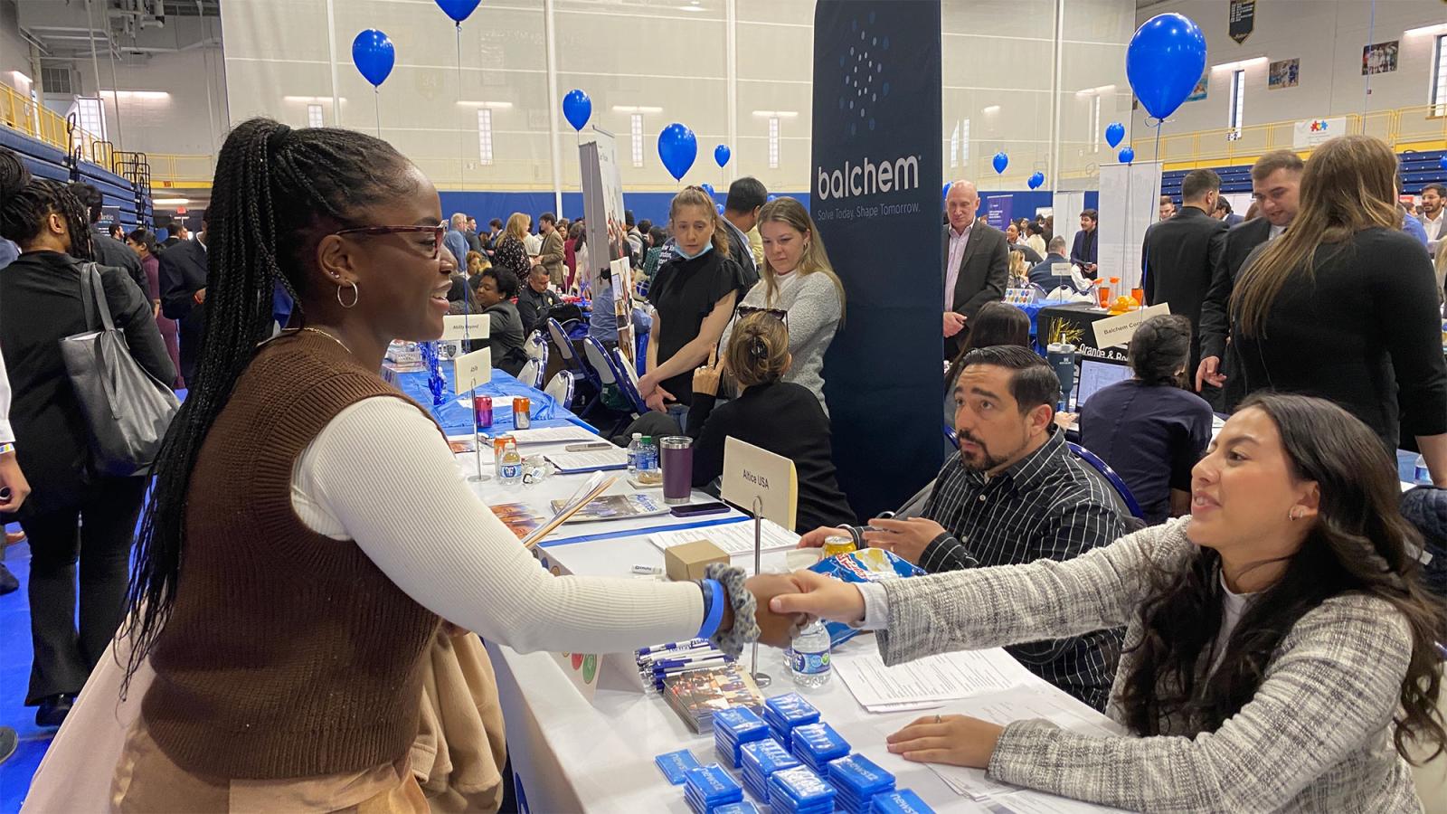 Pace University student at a job fair shaking hands with a potential employer