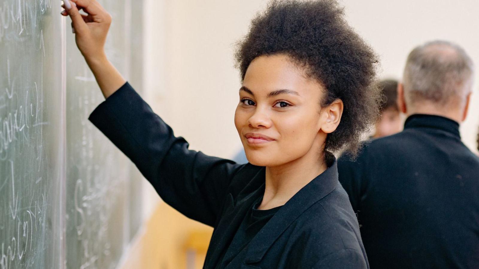 teacher writing on blackboard smiling