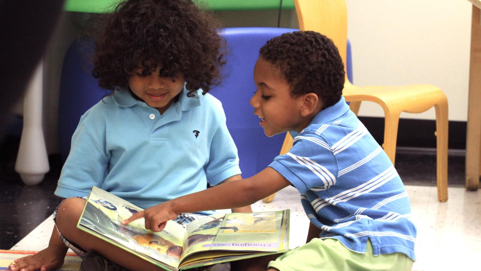 Two preschool children reading a book.