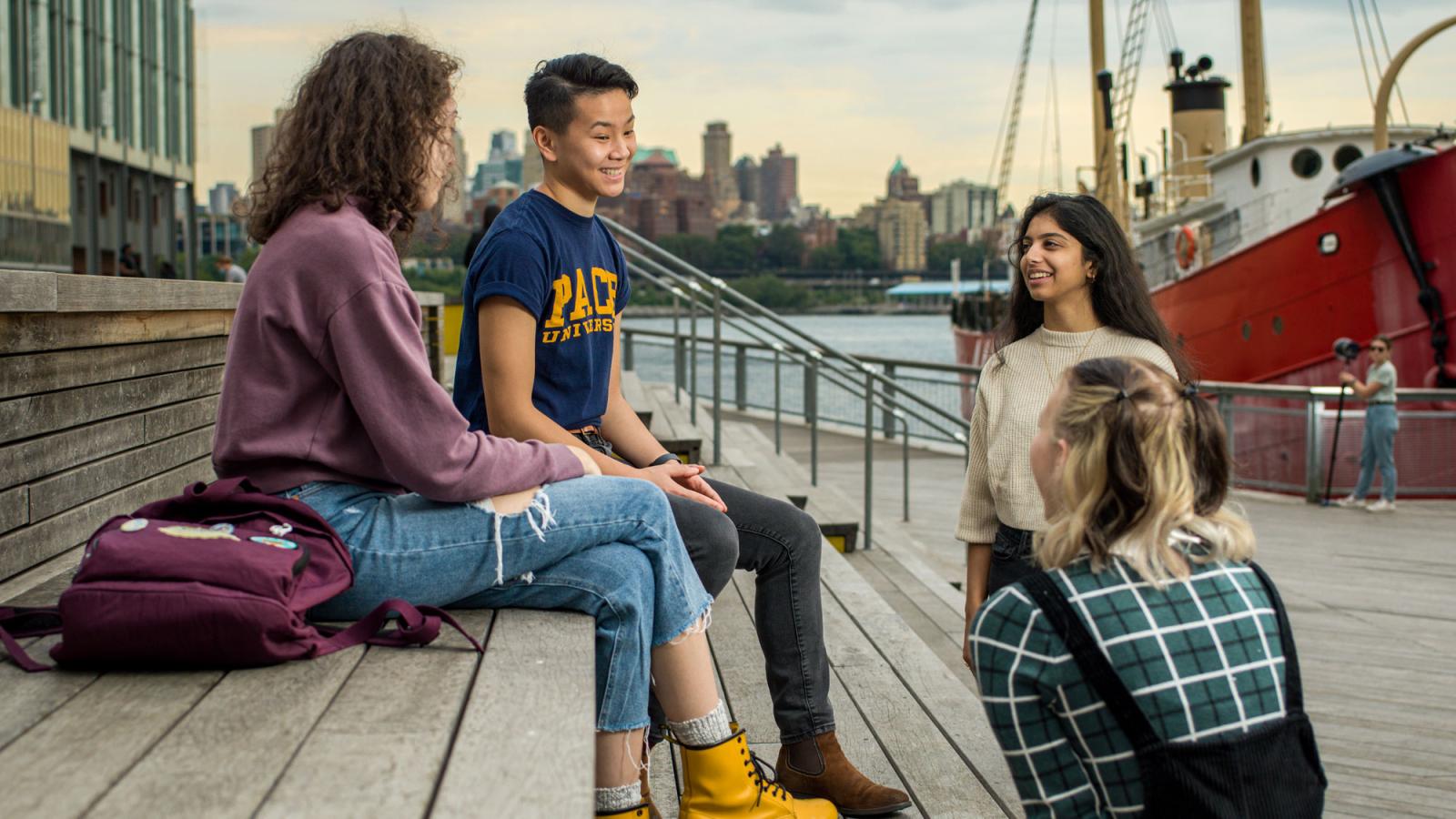 grou of Pace students sitting near the river at the South Street Seaport. 