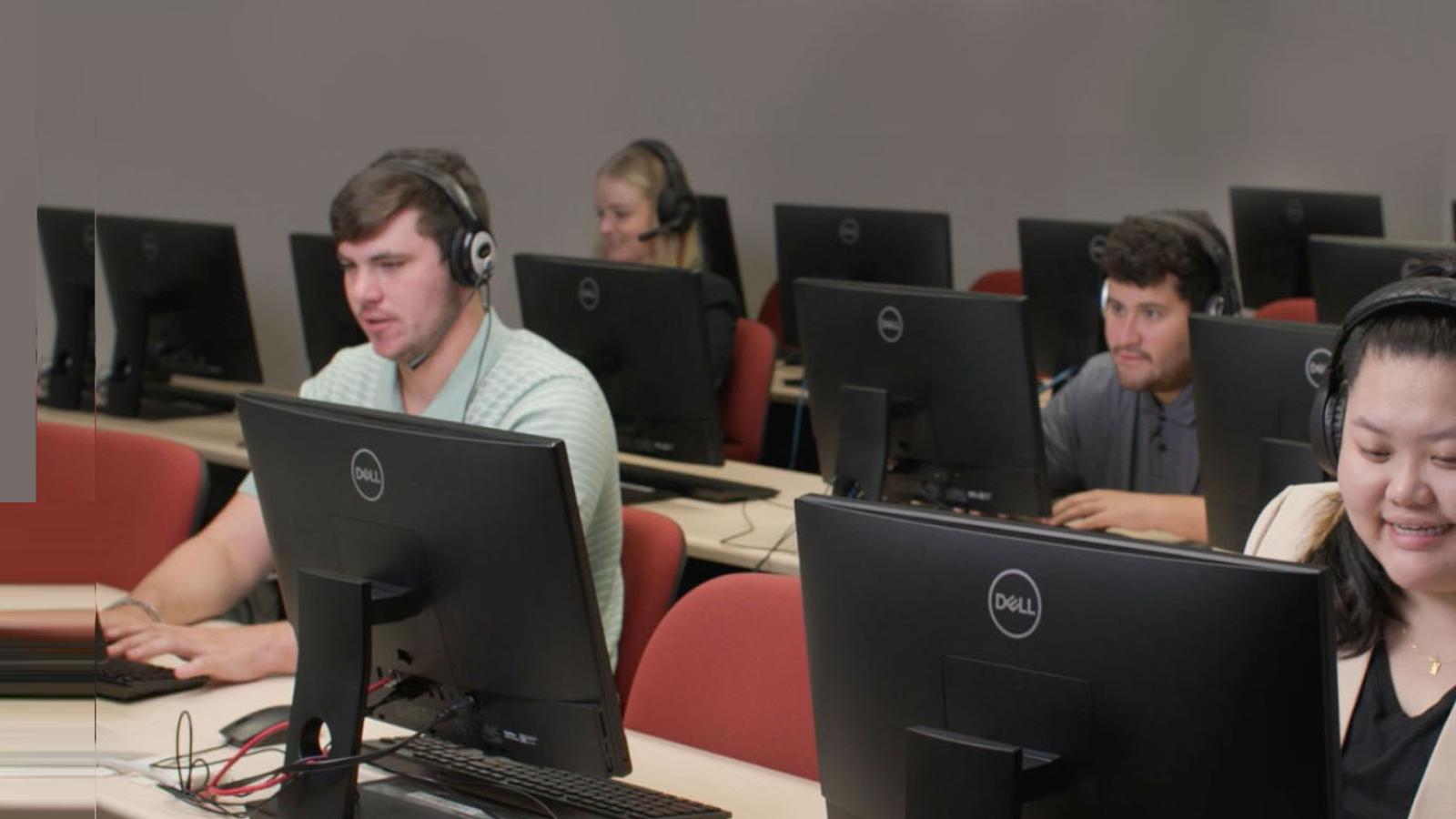 four students working at the Pace Connect call center, wearing headphones and sitting at computers