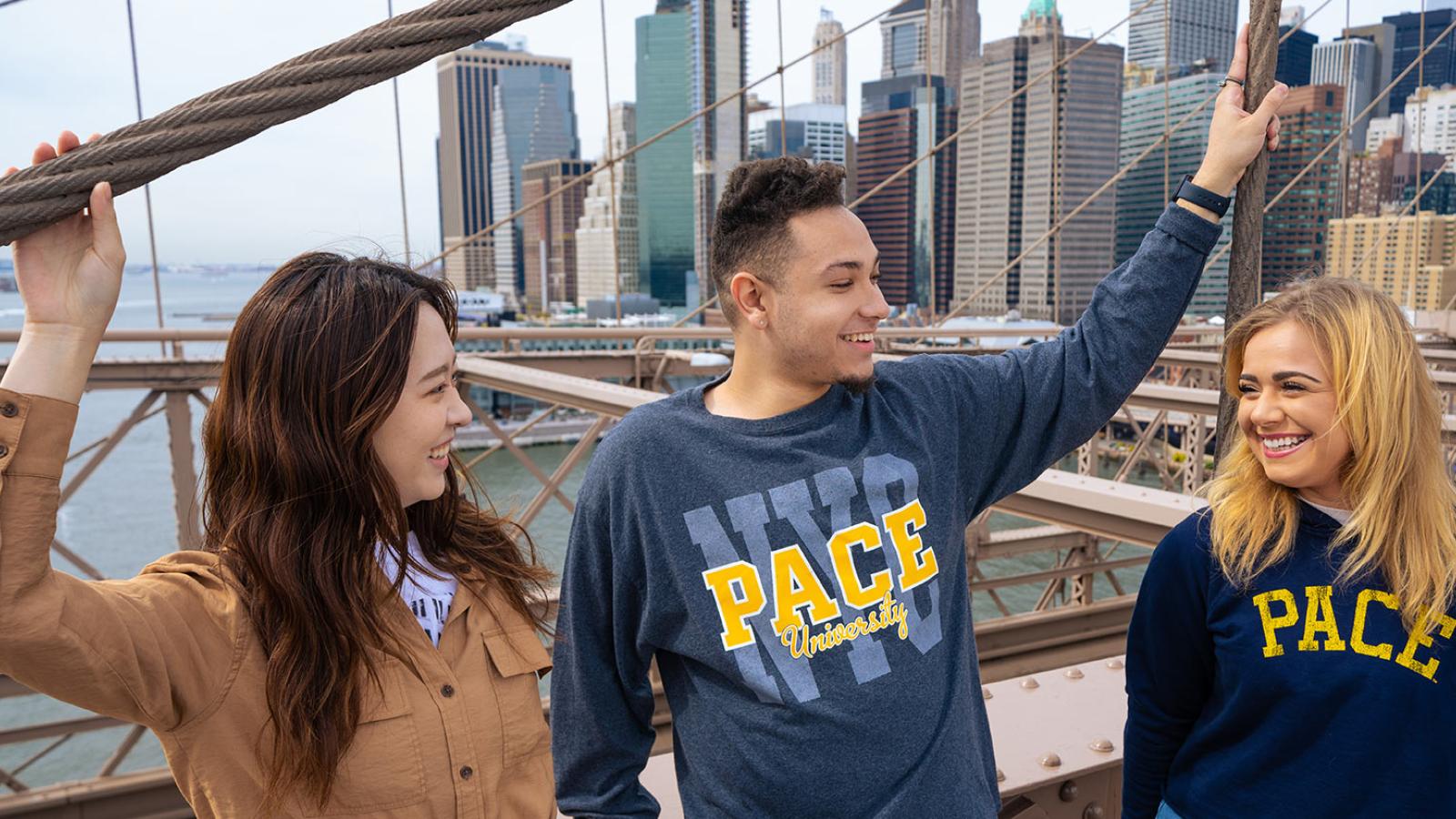 Group of Pace University students at the Brooklyn Bridge talking and laughing.