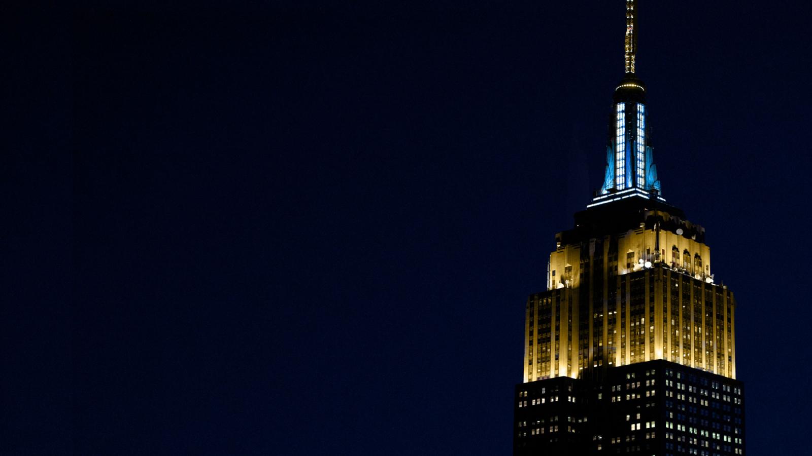 empire state building lights lit up in pace blue and gold