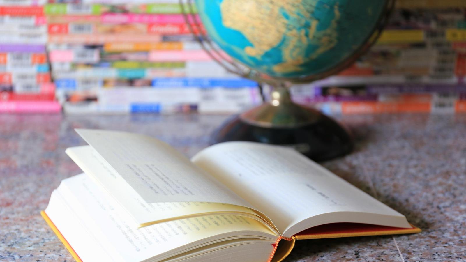 An open book with a globe in the background