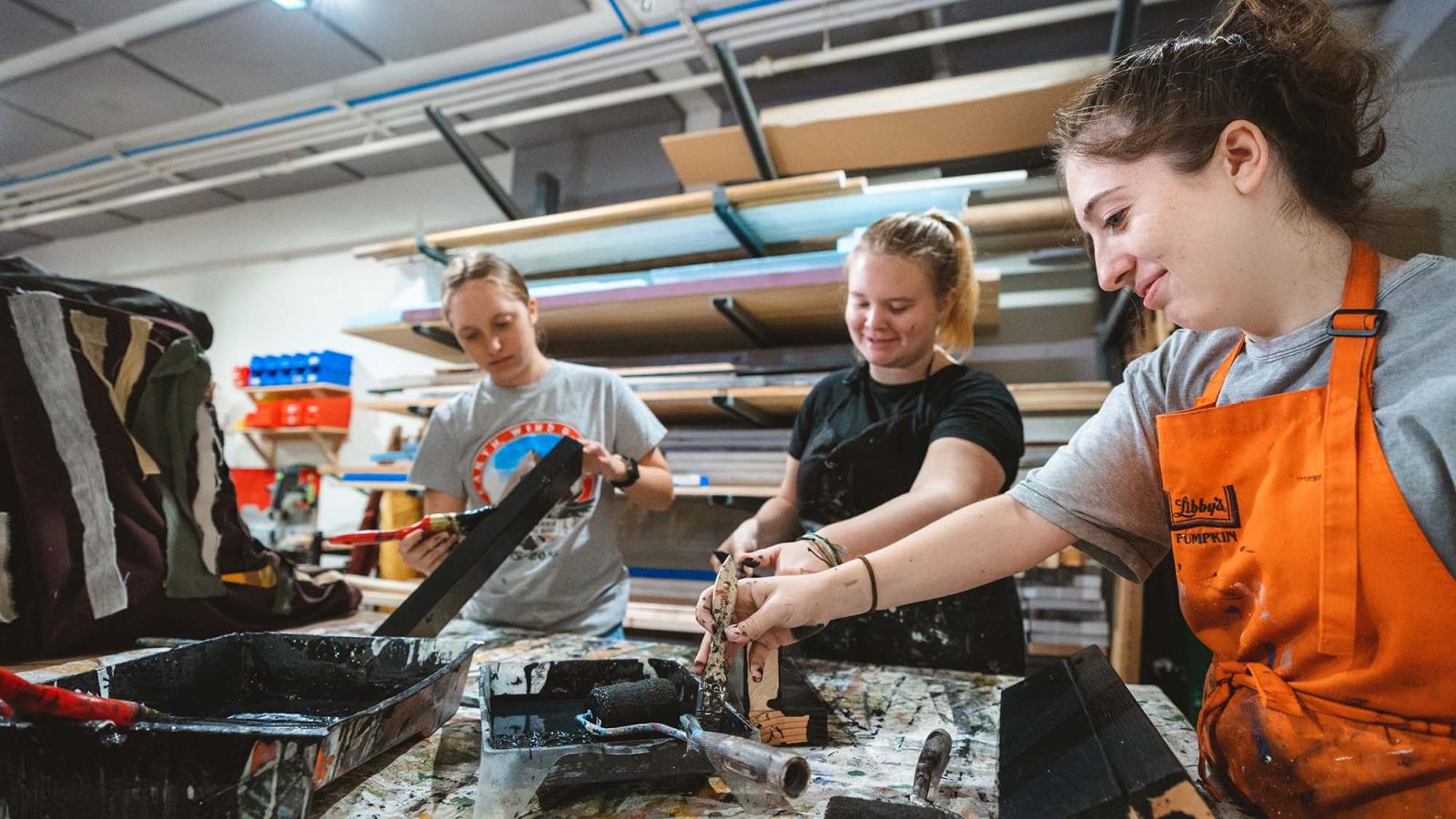 Three Pace students work on prop construction in a workroom