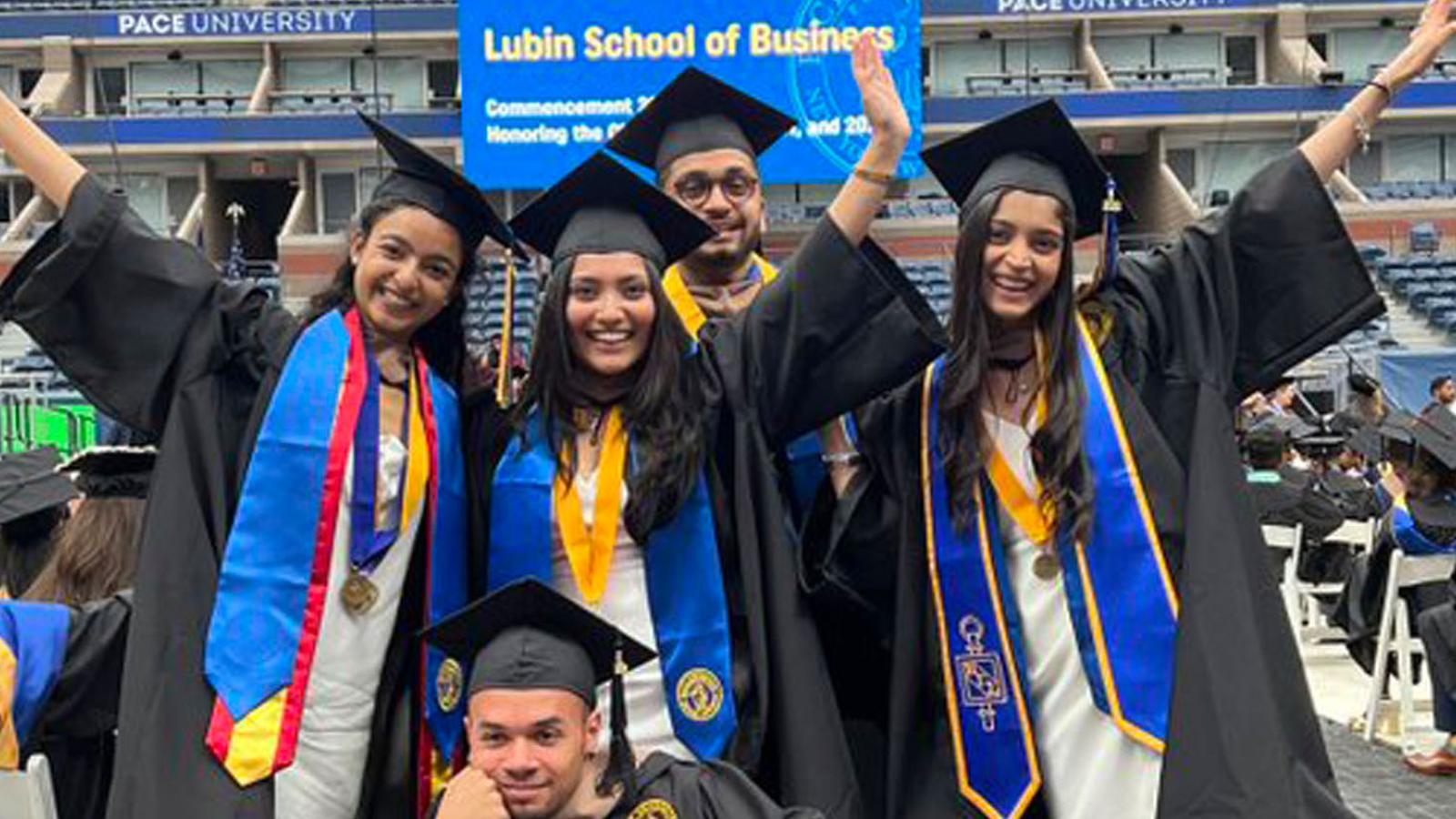 five Lubin students wearing graduation regalia at the 2022 Commencement at the Billie Jean King Tennis Center