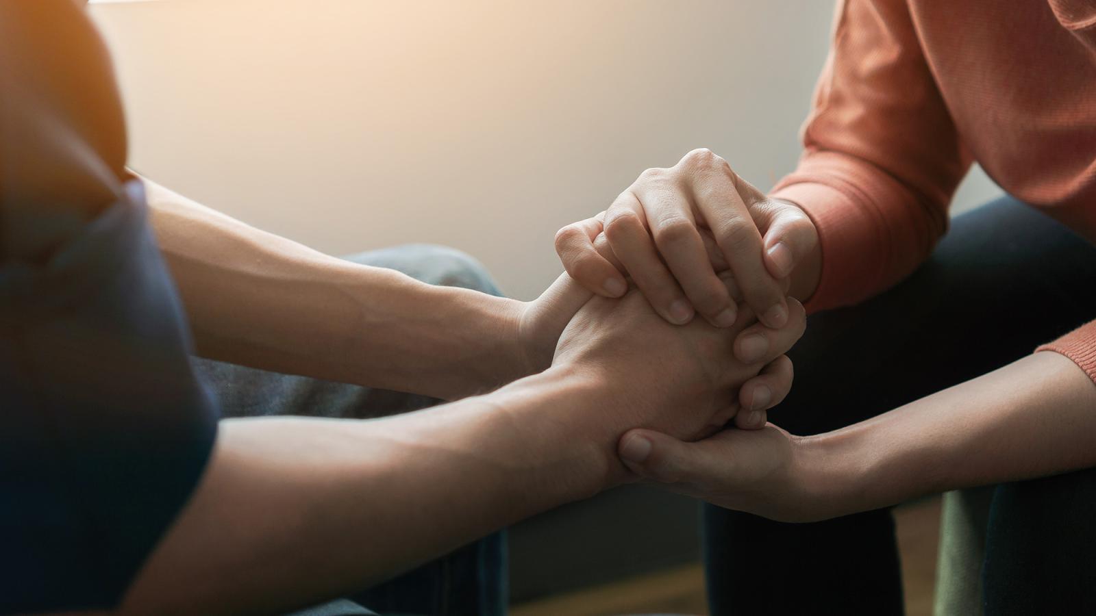 two people hold hands in a gesture of support