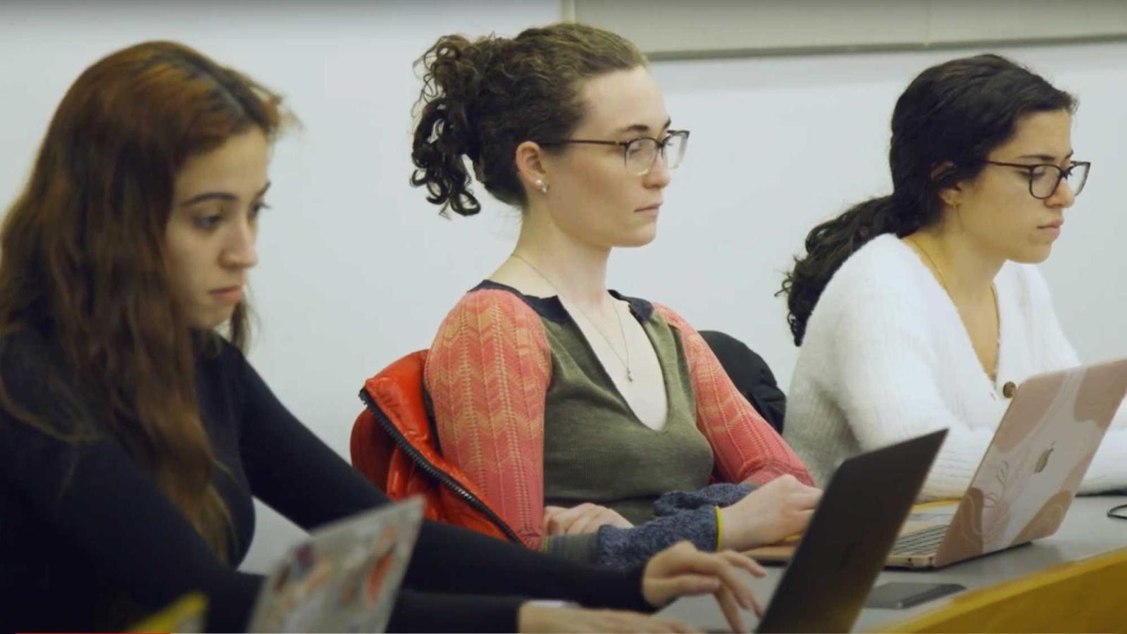three students taking notes on laptops on the Elisabeth Haub School of Law campus