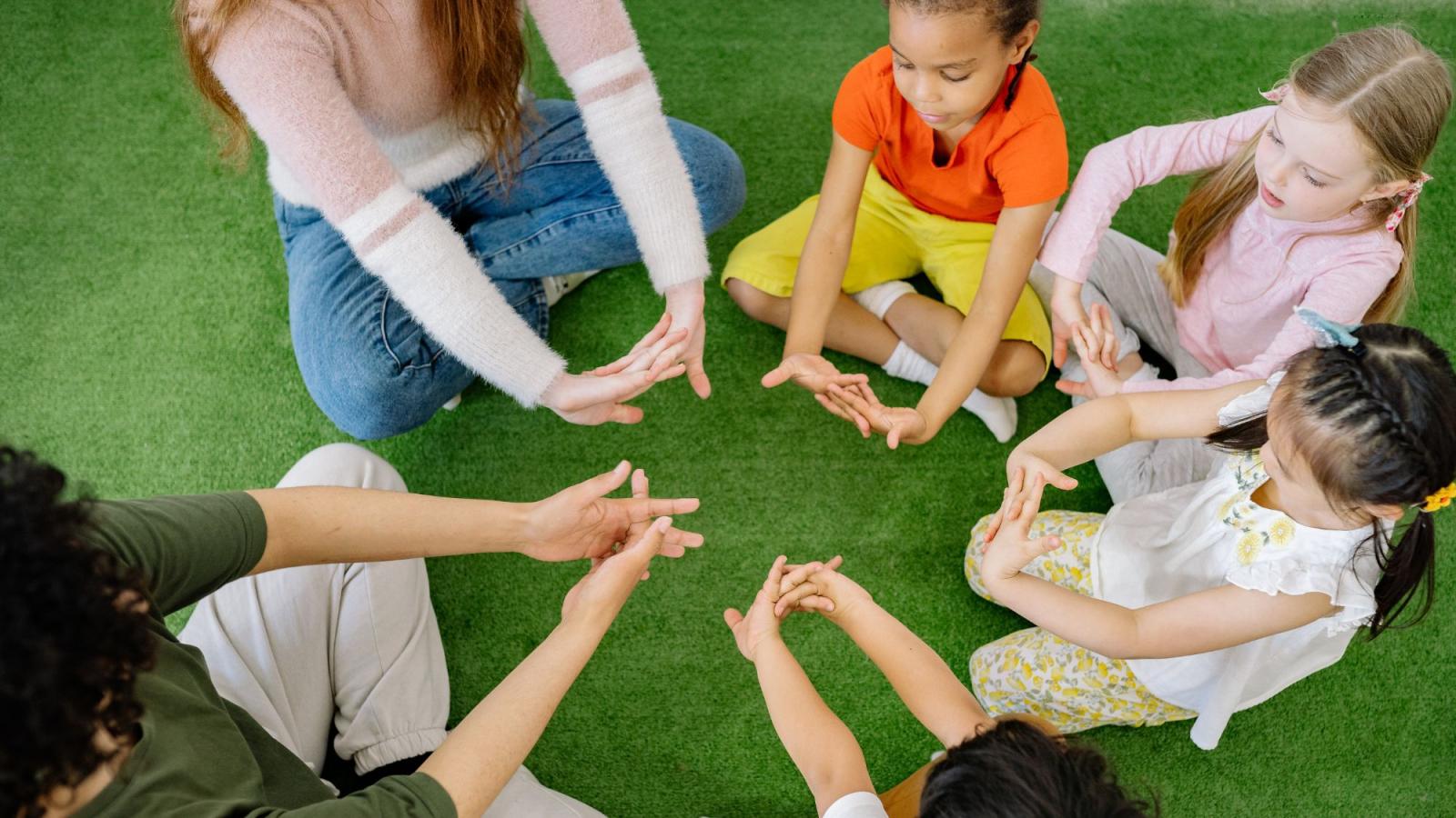 children sitting in a field playing a game with their hands