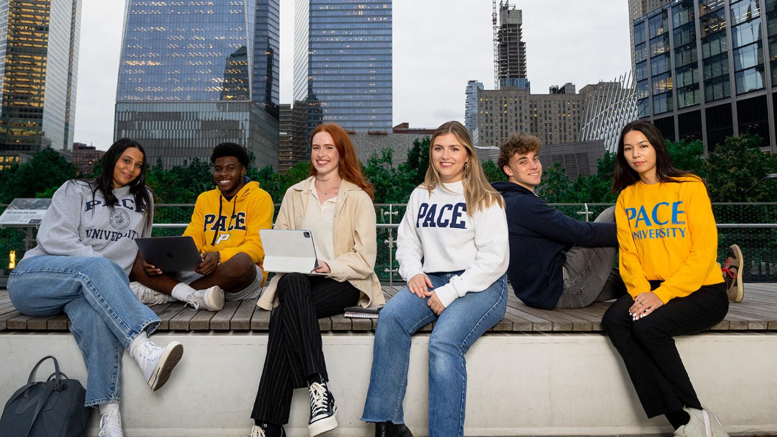 Six Pace University students sitting on a wall in Manhattan