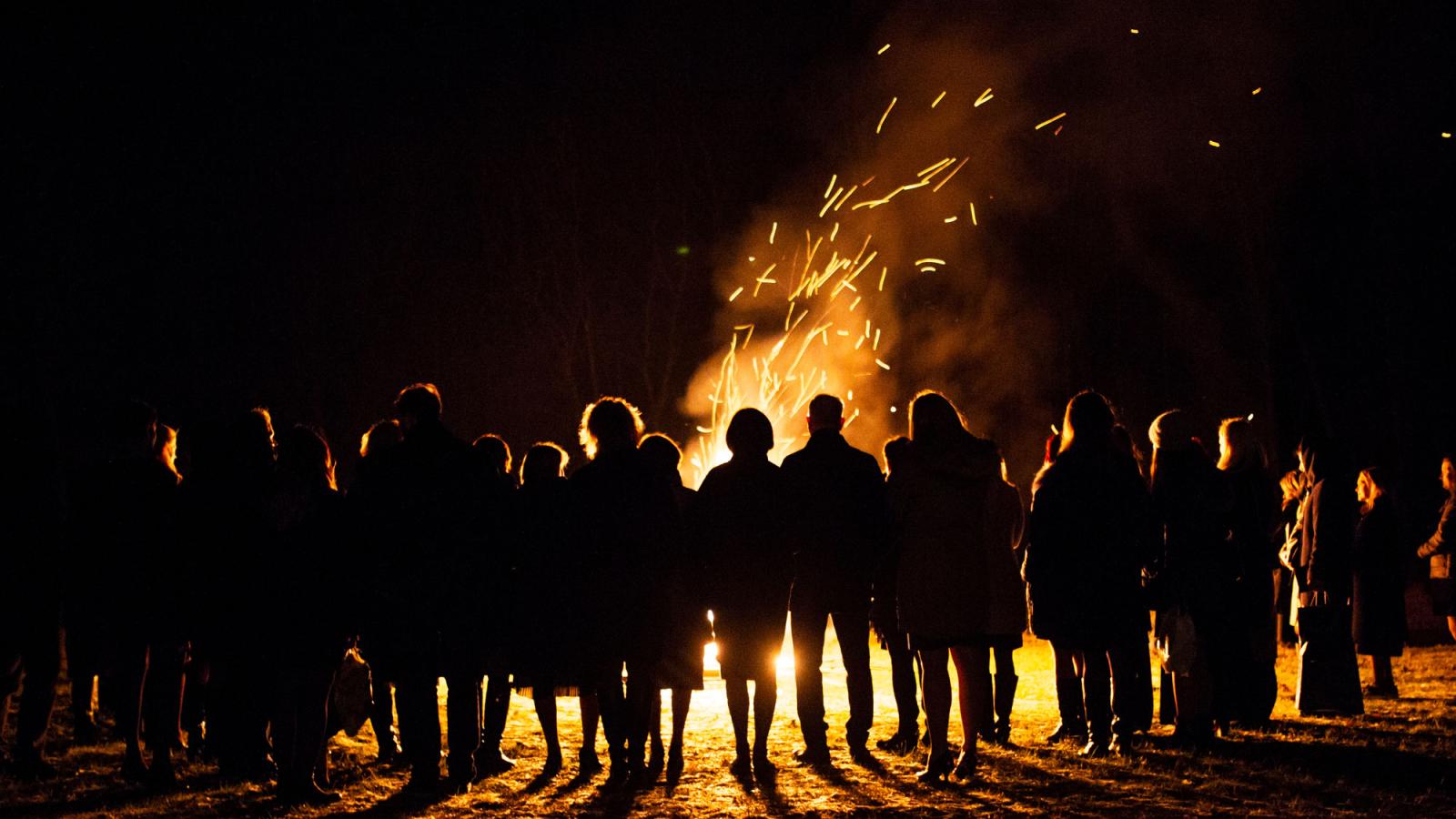 people standing around a bonfire at night