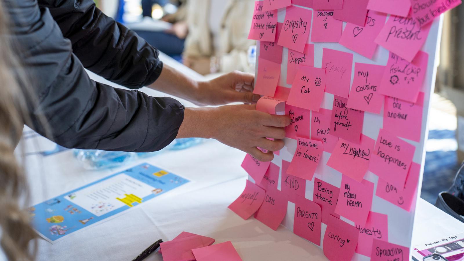 hands putting gratitude notes on a poster board during pace's wellbeing fair.