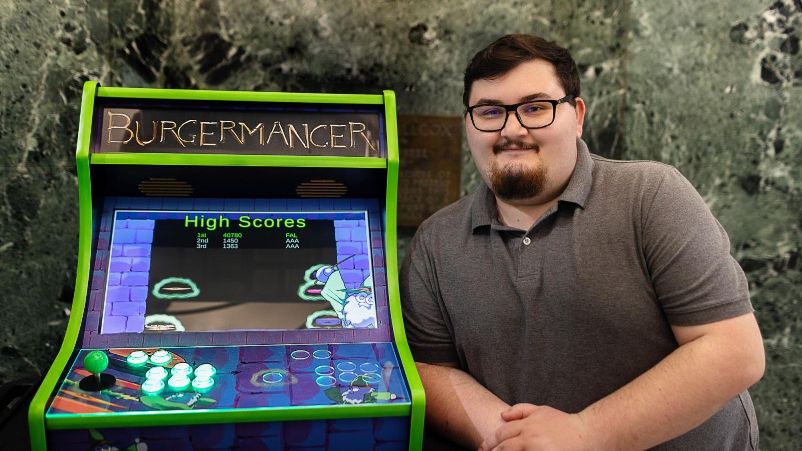 Student Michael Falco beside his hand-built arcade game, BurgerMancer
