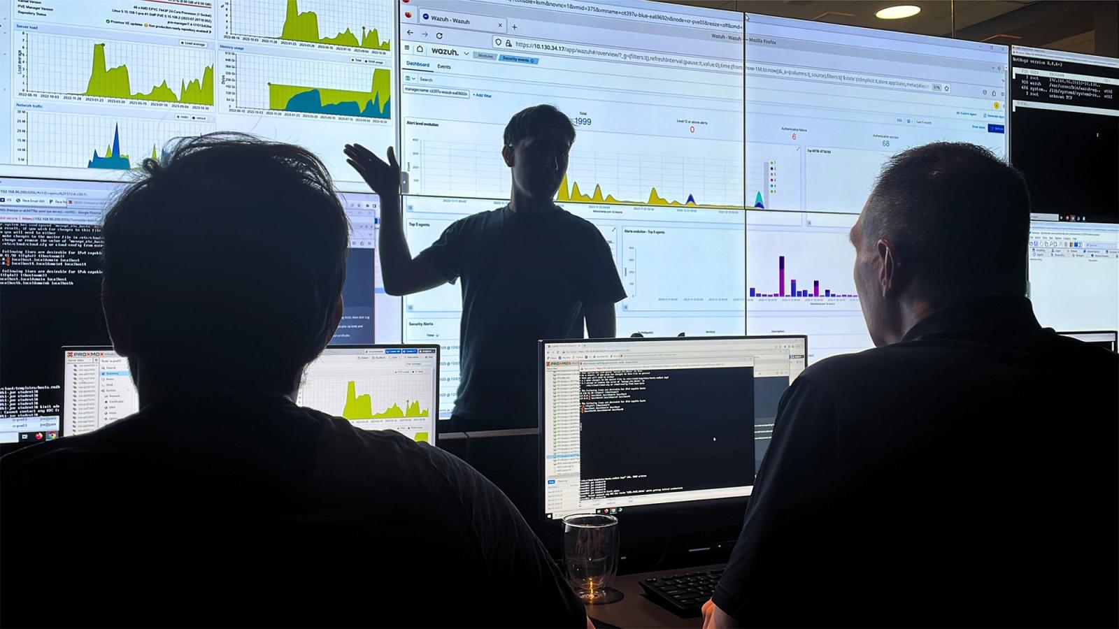 Pace students and professor observing data on large screens in the Pace Cyber Range.