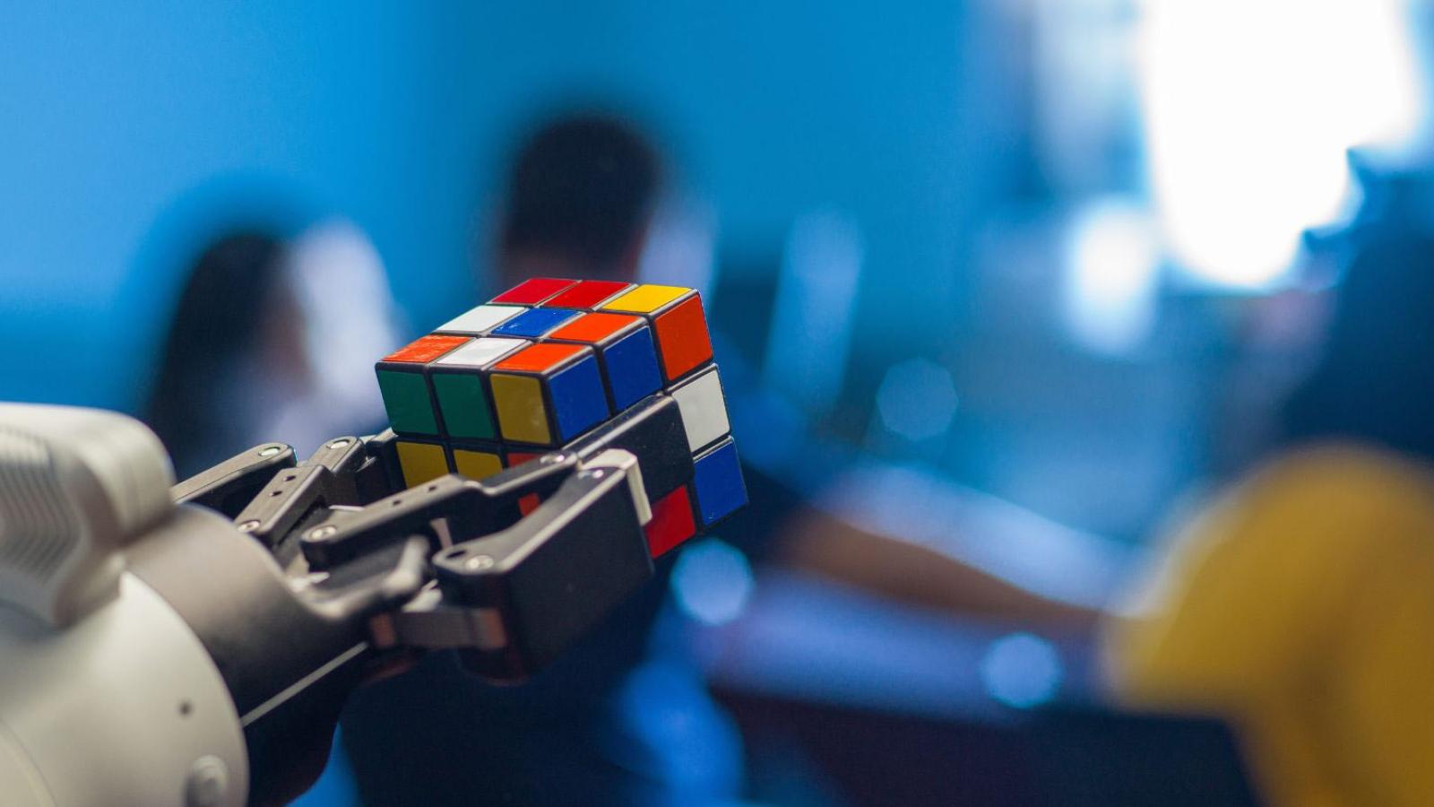 A robot hand holds a rubix cube.