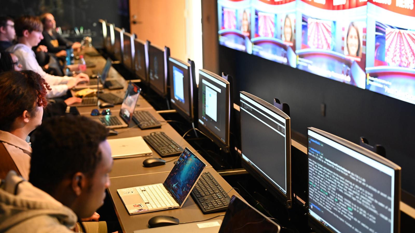 Pace students working in front of a row of computers within the Cyber Range