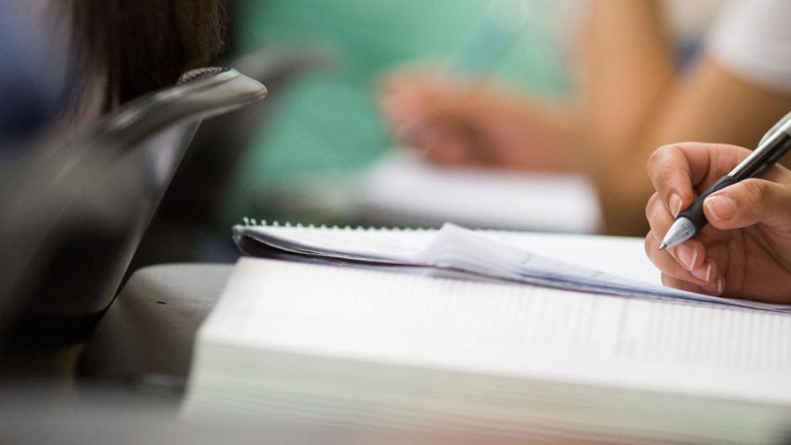 close-up of Lubin student writing at a desk in a classroom on the New York City Campus