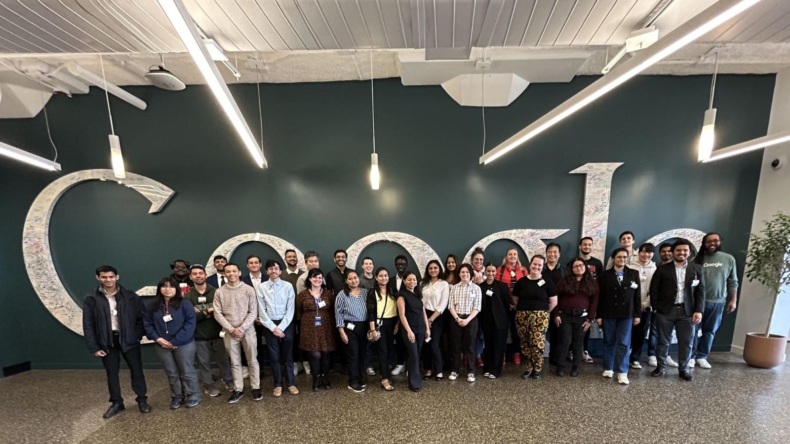 Pace Seidenberg students, faculty, and staff posing in front of the Google logo at the Google New York City office.