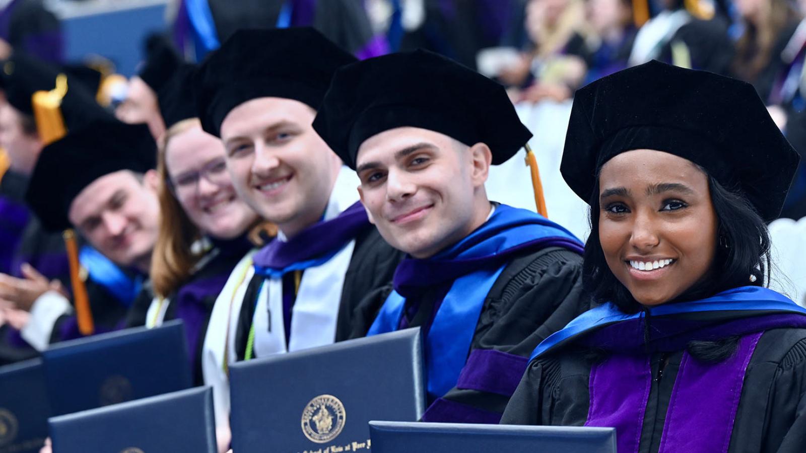 Elisabeth Haub School of Law students posing with their degrees at commencement.