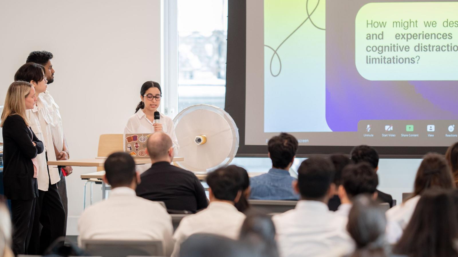 A group of Pace Seidenberg students showcasing a Powerpoint presentation of their Design Factory project to an audience at the Design Factory Gala.