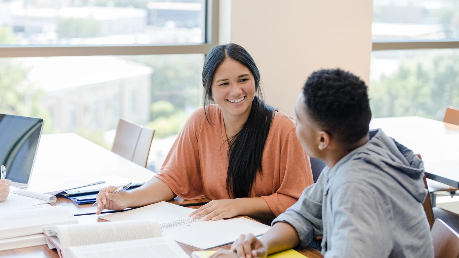 Two individuals conversing at conference table at the Elisabeth Haub School of Law