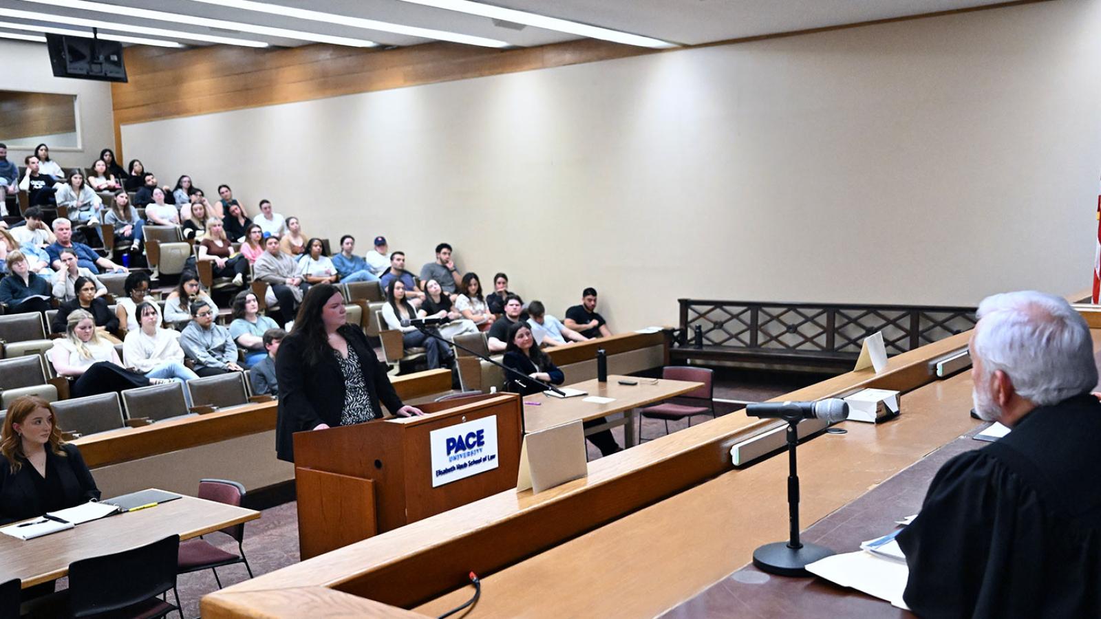 Court room with judges and an Elisabeth Haub School of Law student at the Moot Court Competition