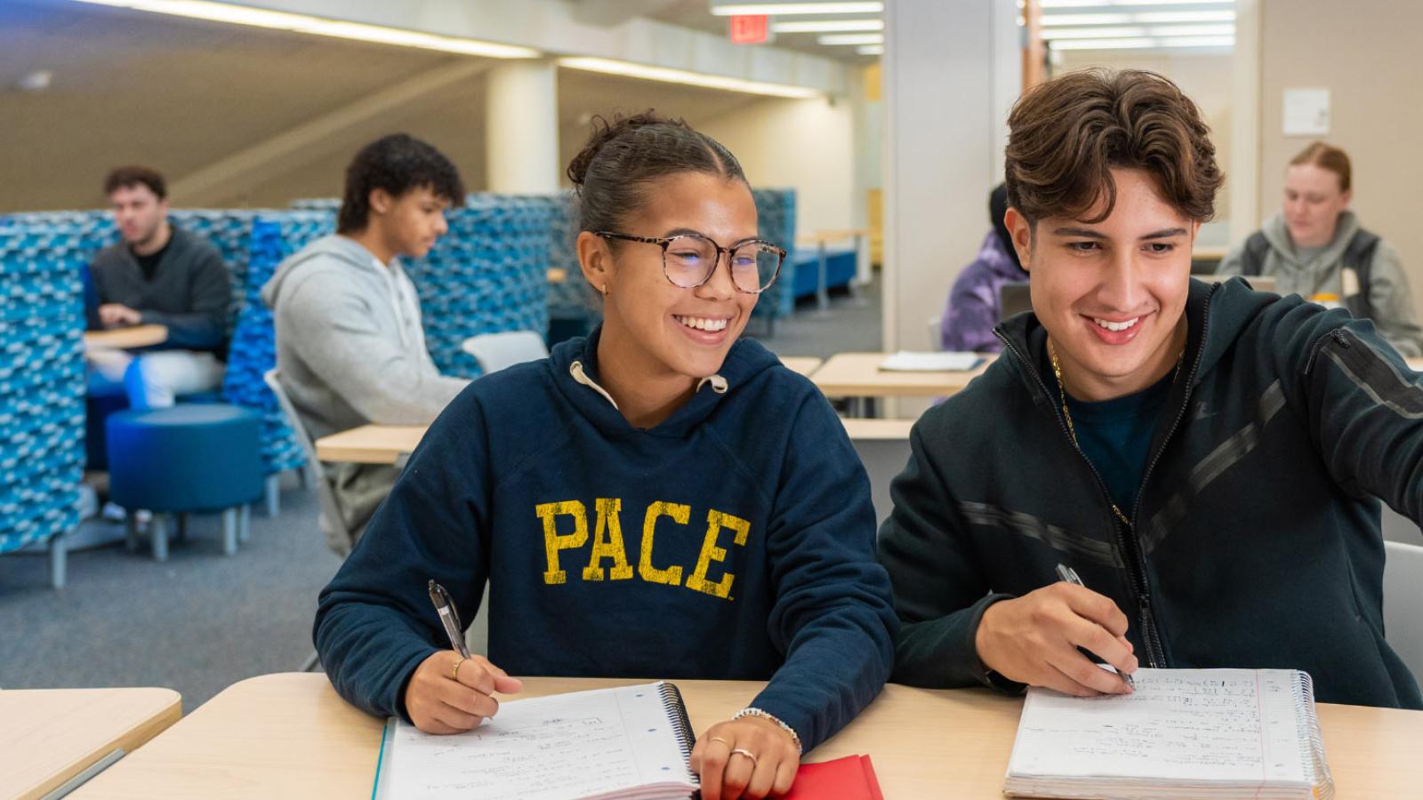 Two students sitting at a table at the Pleasantville campus looking at their laptop.