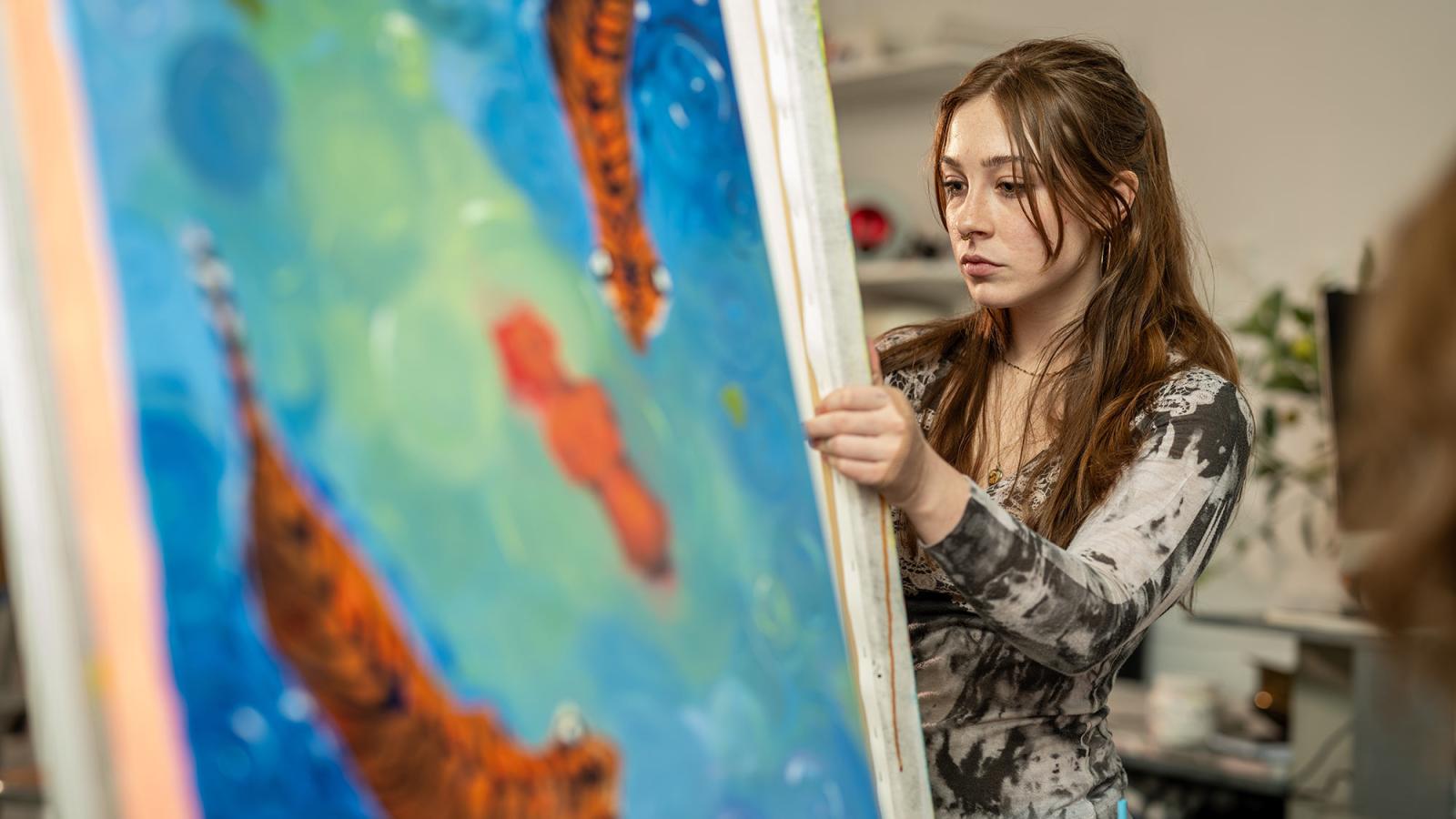 Pace University student Abby Arena reviews her painting 