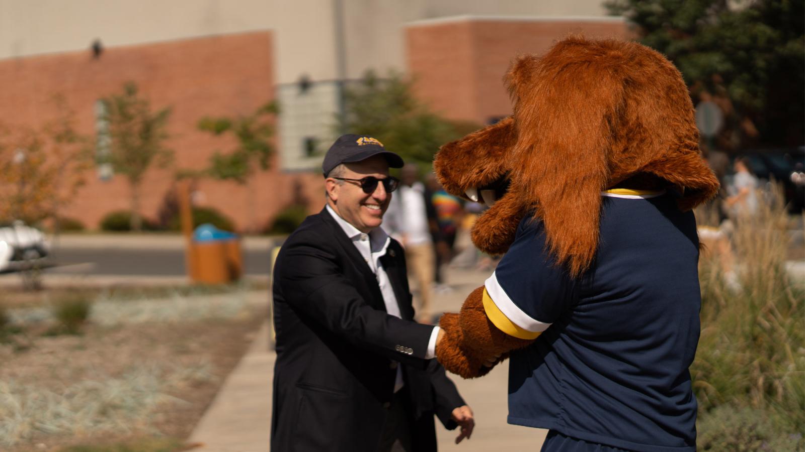 Pace University President Marvin Krislov shaking hands with the Pace mascot, T-Bone.