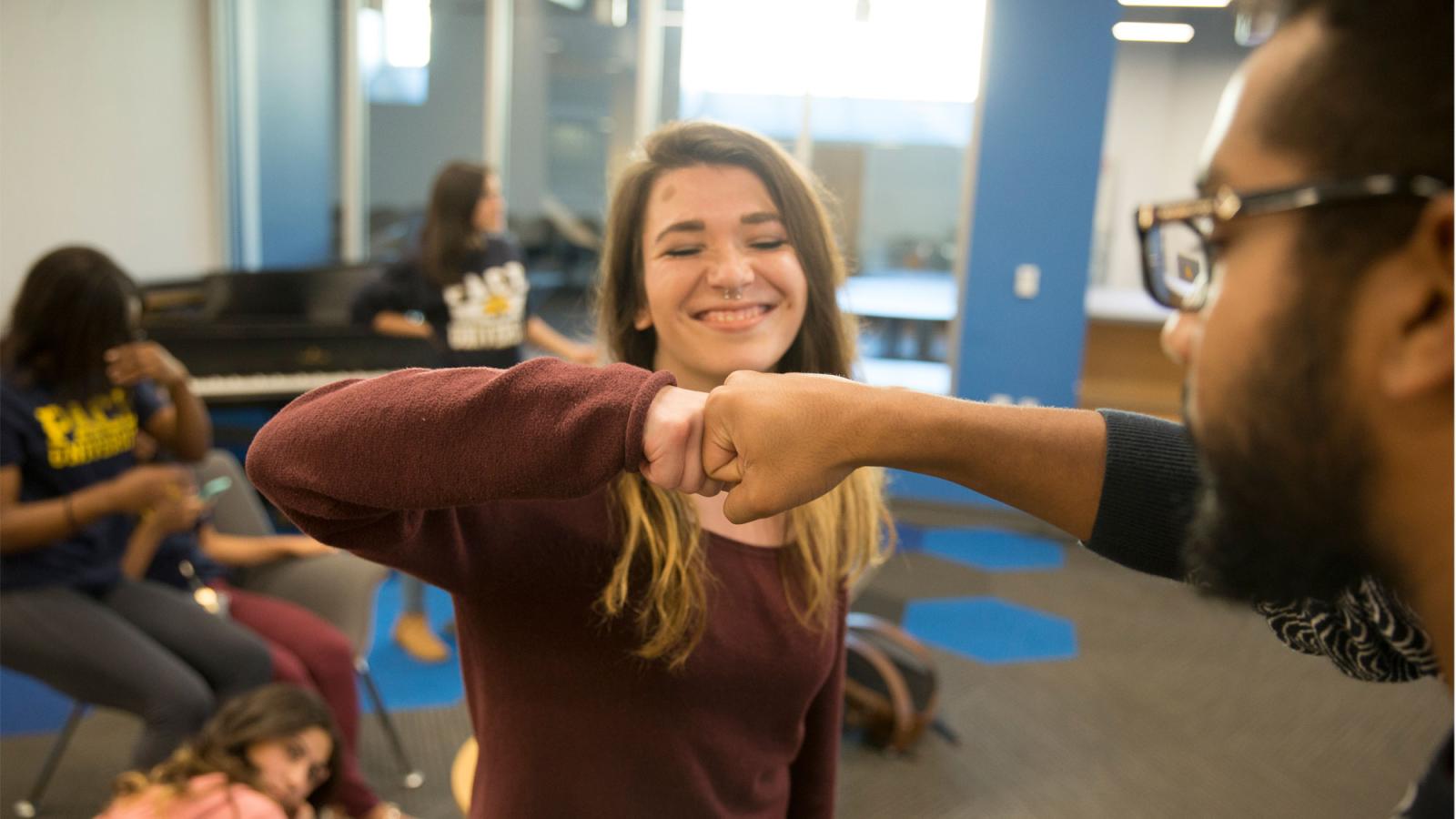 Two Pace University students fist-bumping on the Pleasantville Campus.
