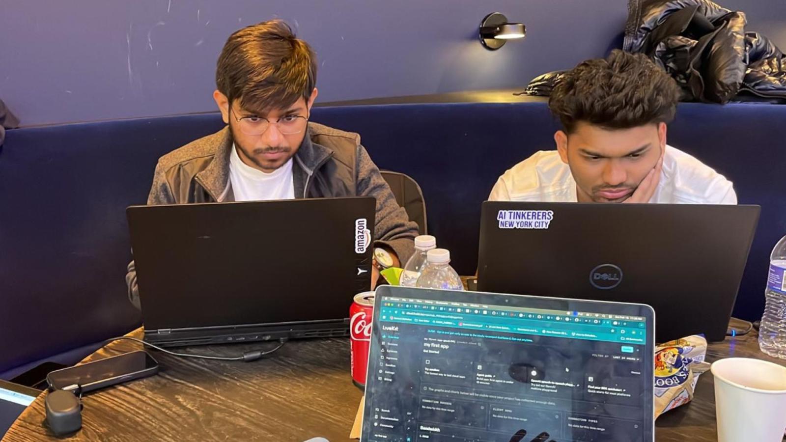 Two students from Pace University's Seidenberg School of CSIS Data Science Club sitting at a table and looking at their laptops while coding.