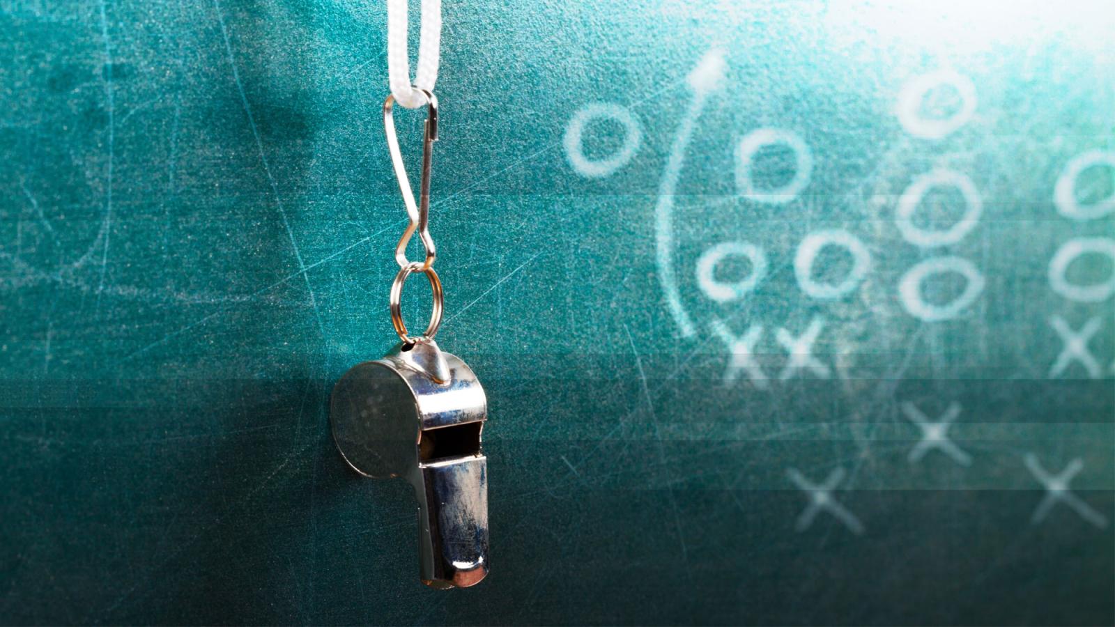 Whistle dangling against a blackboard.